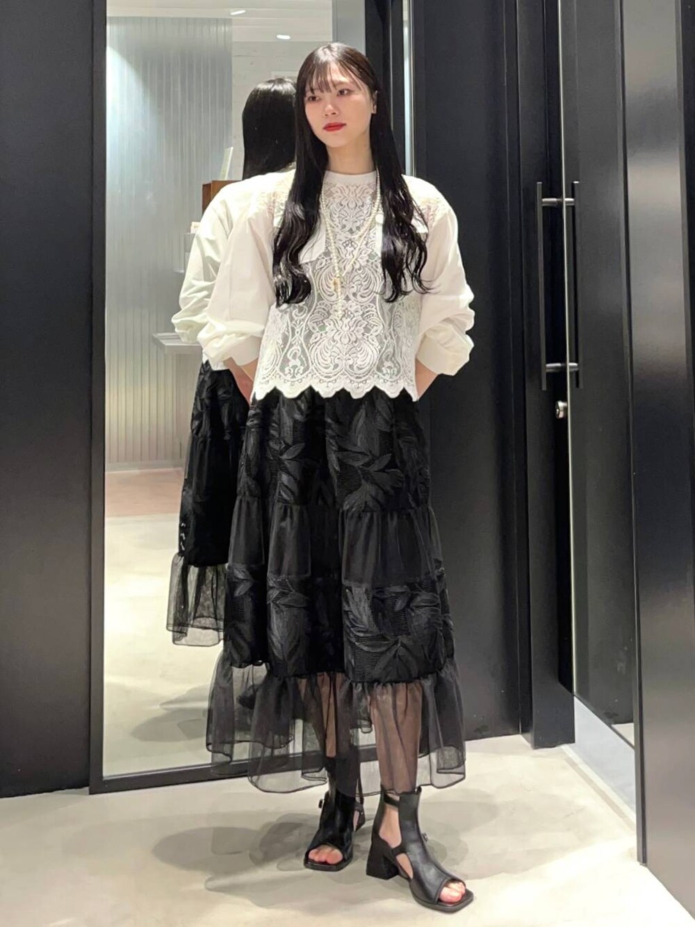 ホワイト系のTシャツ/カットソー、ブラック系のサンダル、ブラック系のスカートを着用したレディースの春コーディネートの1枚目の写真