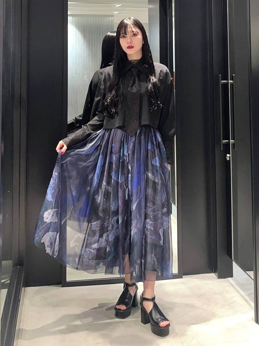 ブラック系のサンダル、ブラック系のシャツ/ブラウス、パープル系のスカートを着用したレディースの春コーディネートの1枚目の写真