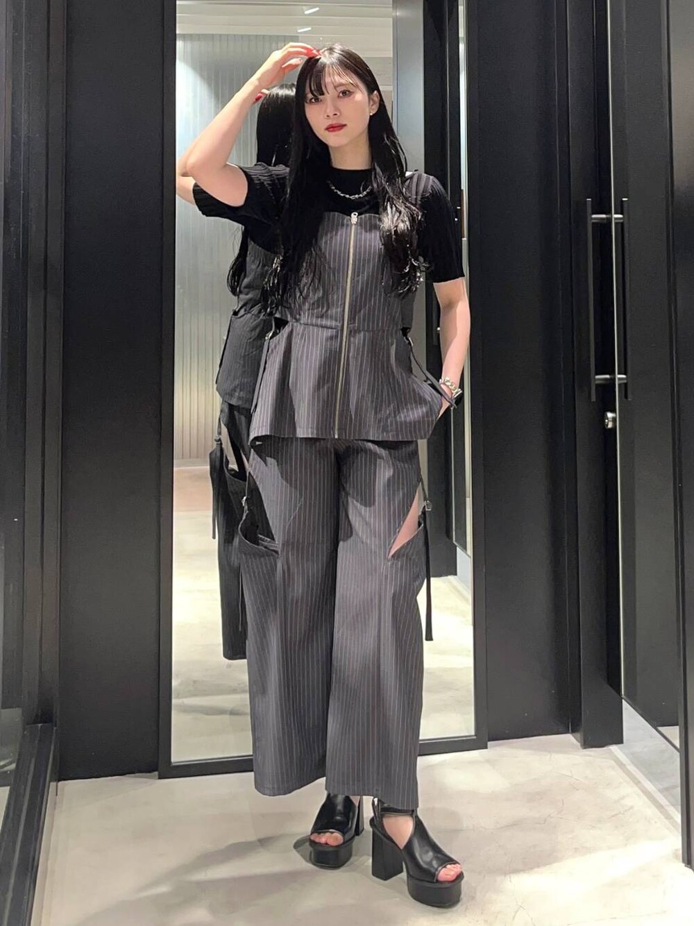 ブラック系のサンダル、ブラック系のニット/セーター、グレー系のベストを着用したレディースの春コーディネートの1枚目の写真