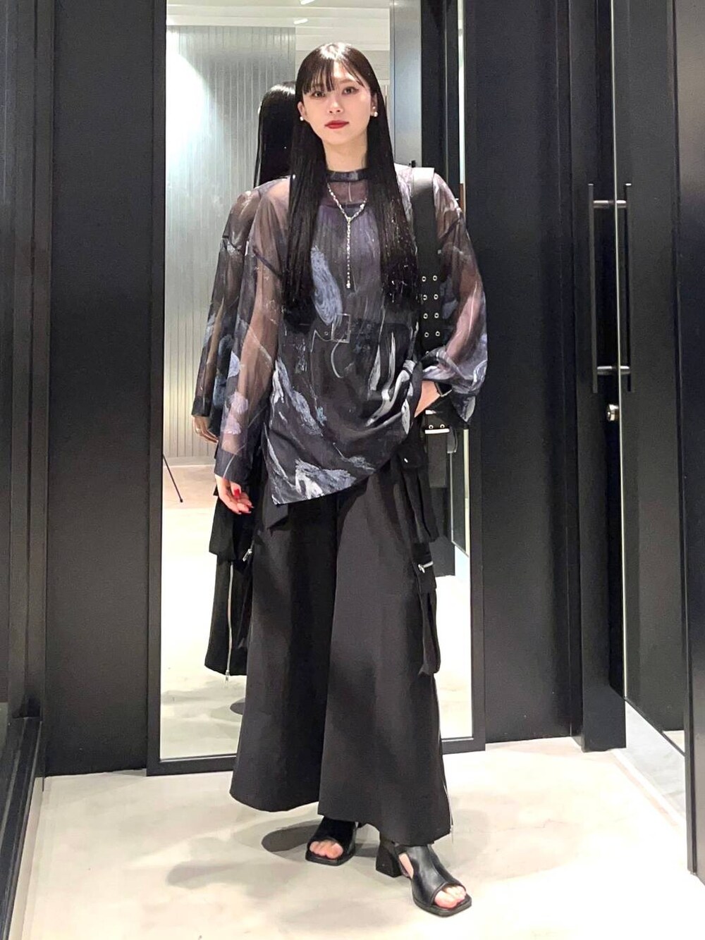 ブラック系のカーゴパンツ、ブラック系のショルダーバッグ、ブラック系のサンダルを着用したレディースの春コーディネートの1枚目の写真