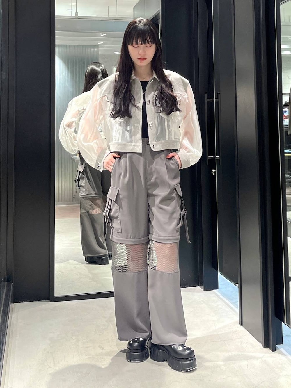 ホワイト系のブルゾン、ブラック系のサンダル、グレー系のカーゴパンツを着用したレディースの春コーディネートの1枚目の写真