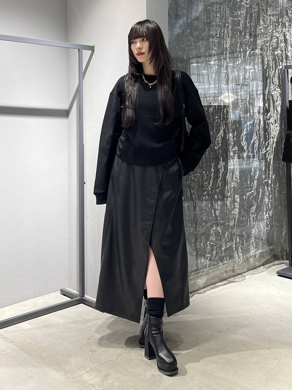 ブラック系のバックパック/リュック、ブラック系のスカート、ブラック系のブーツを着用したレディースの秋コーディネートの1枚目の写真