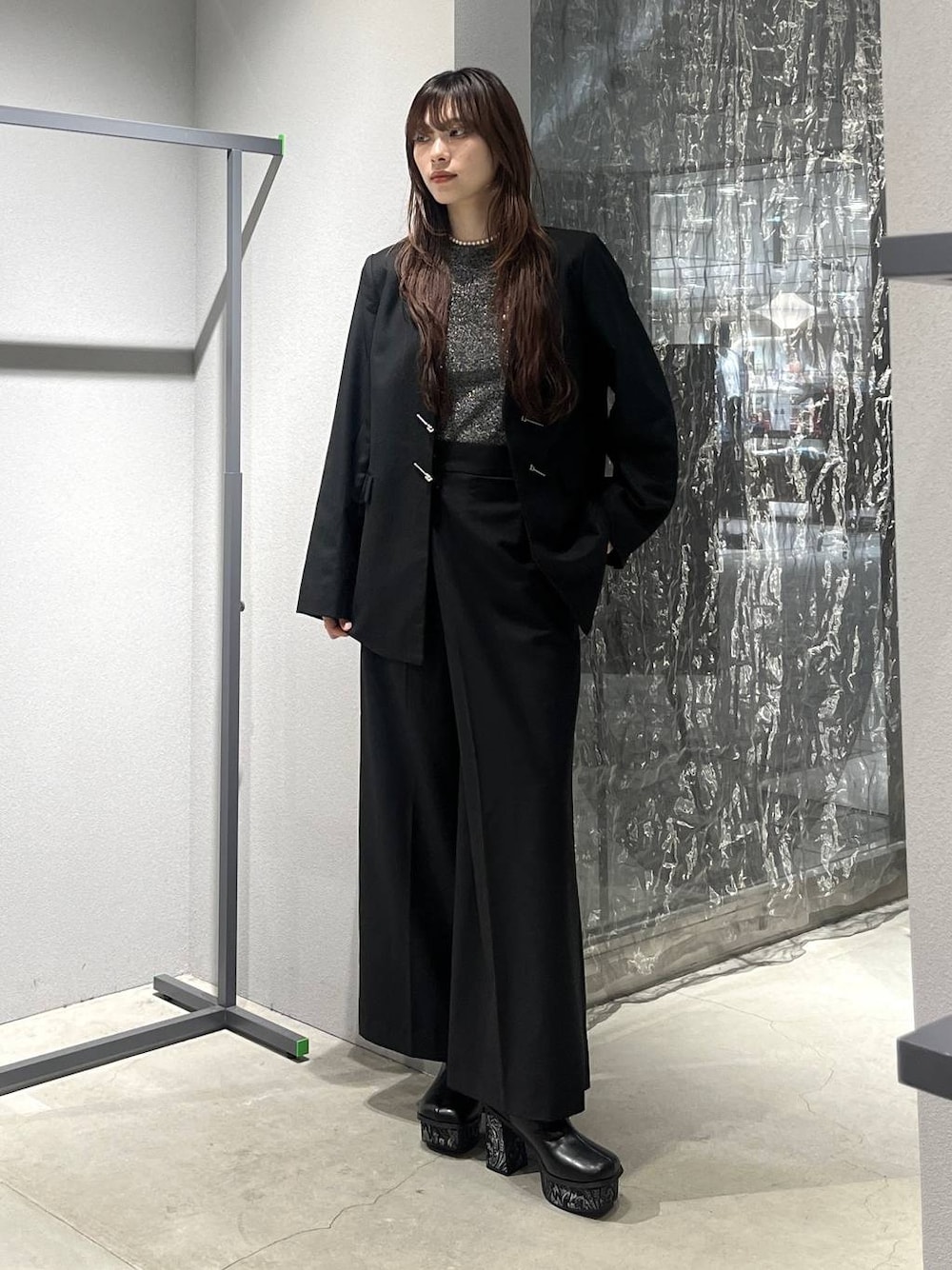 グレー系のブーツ、ブラック系のノーカラージャケット、ブラック系のスラックスを着用したレディースの秋コーディネートの1枚目の写真