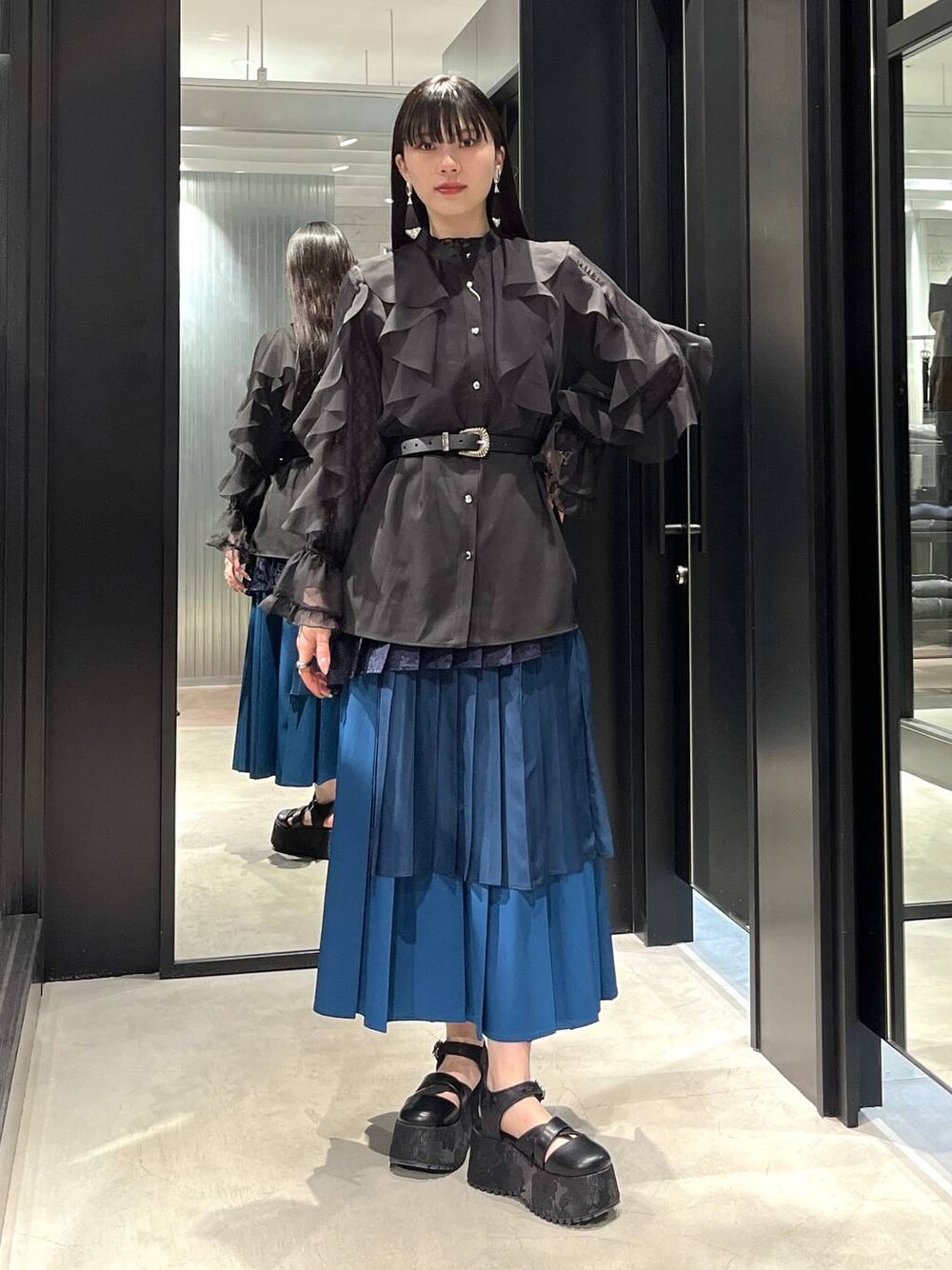 ブラック系のサンダル、ブラック系のシャツ/ブラウス、ブルー系のスカートを着用したレディースの春コーディネートの1枚目の写真