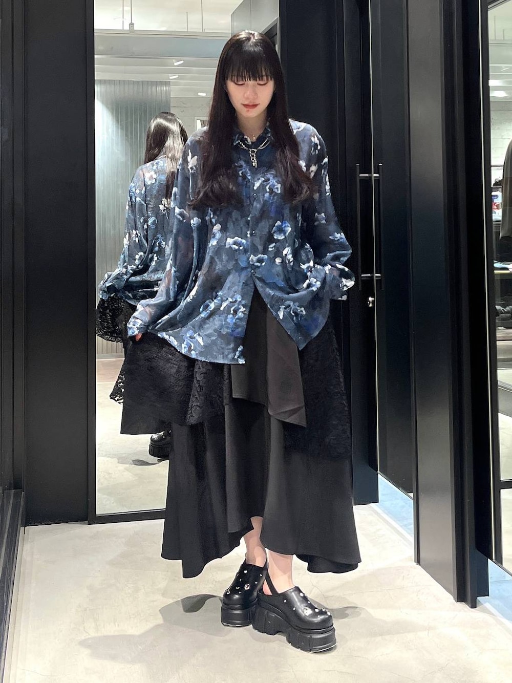 ブラック系のスカート、ブラック系のサンダル、シルバー系のネックレスを着用したレディースの春コーディネートの1枚目の写真