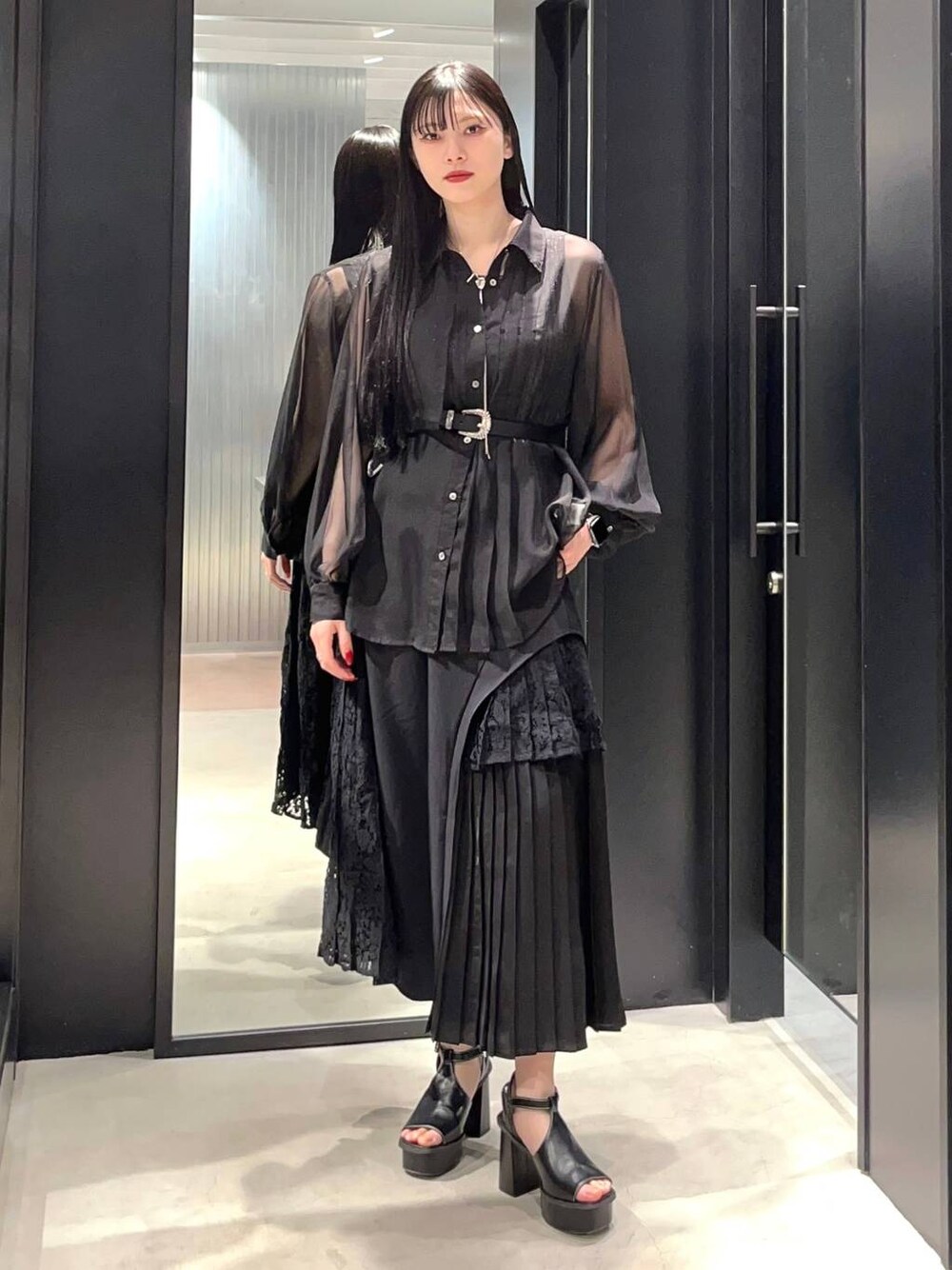 ブラック系のサンダル、ブラック系のシャツ/ブラウス、ブラック系のスカートを着用したレディースの春コーディネートの1枚目の写真