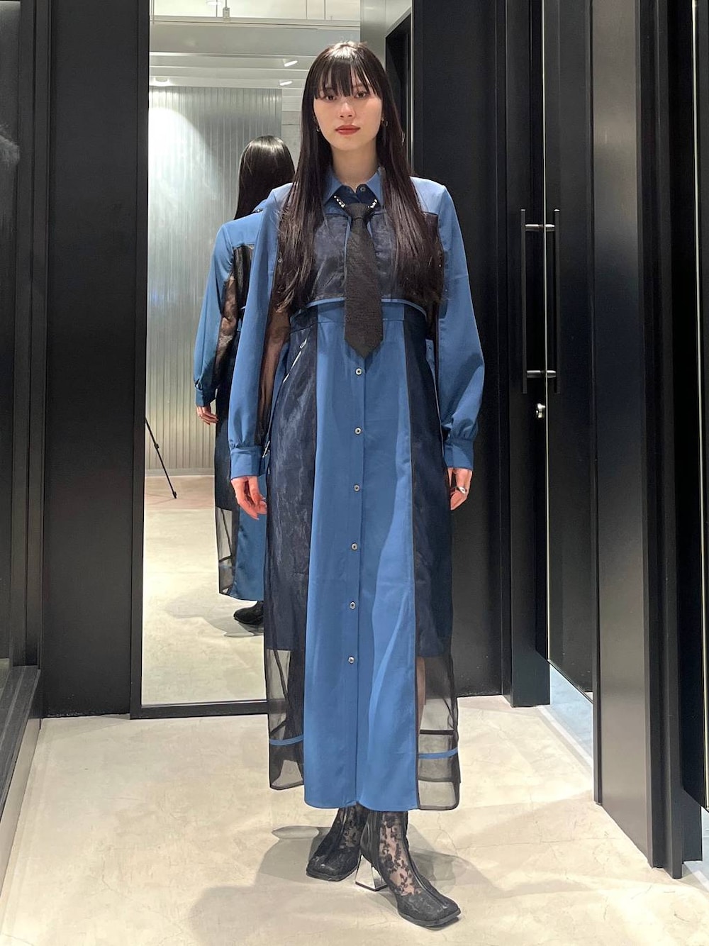 ブラック系のネクタイ、ブラック系のブーツ、ブルー系のワンピースを着用したレディースの春コーディネートの1枚目の写真