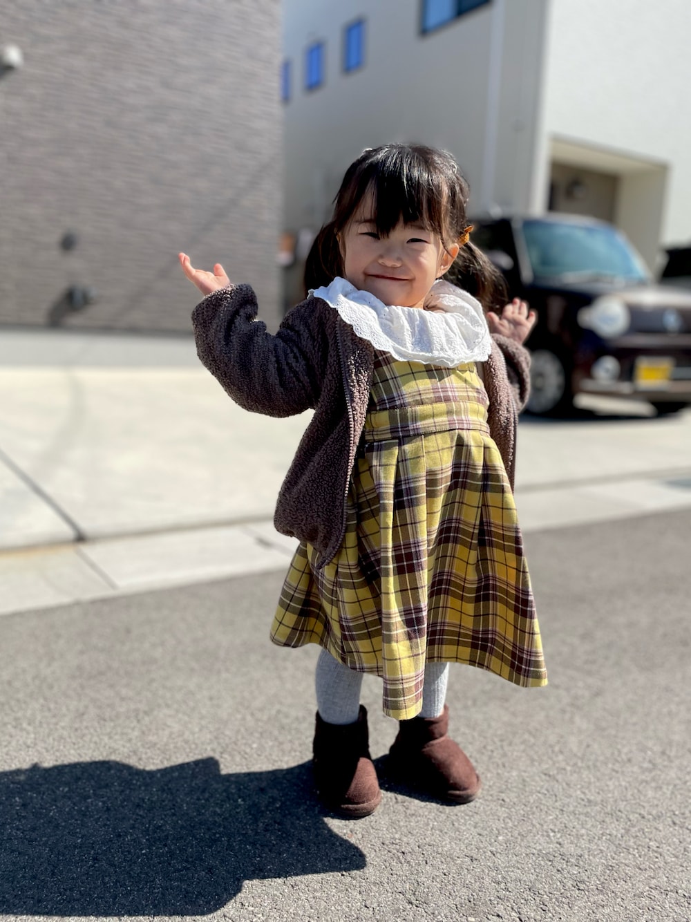 イエロー系のジャンパースカート、ブラウン系のTシャツ/カットソー、ブラウン系のブーツを着用したキッズの春コーディネートの1枚目の写真