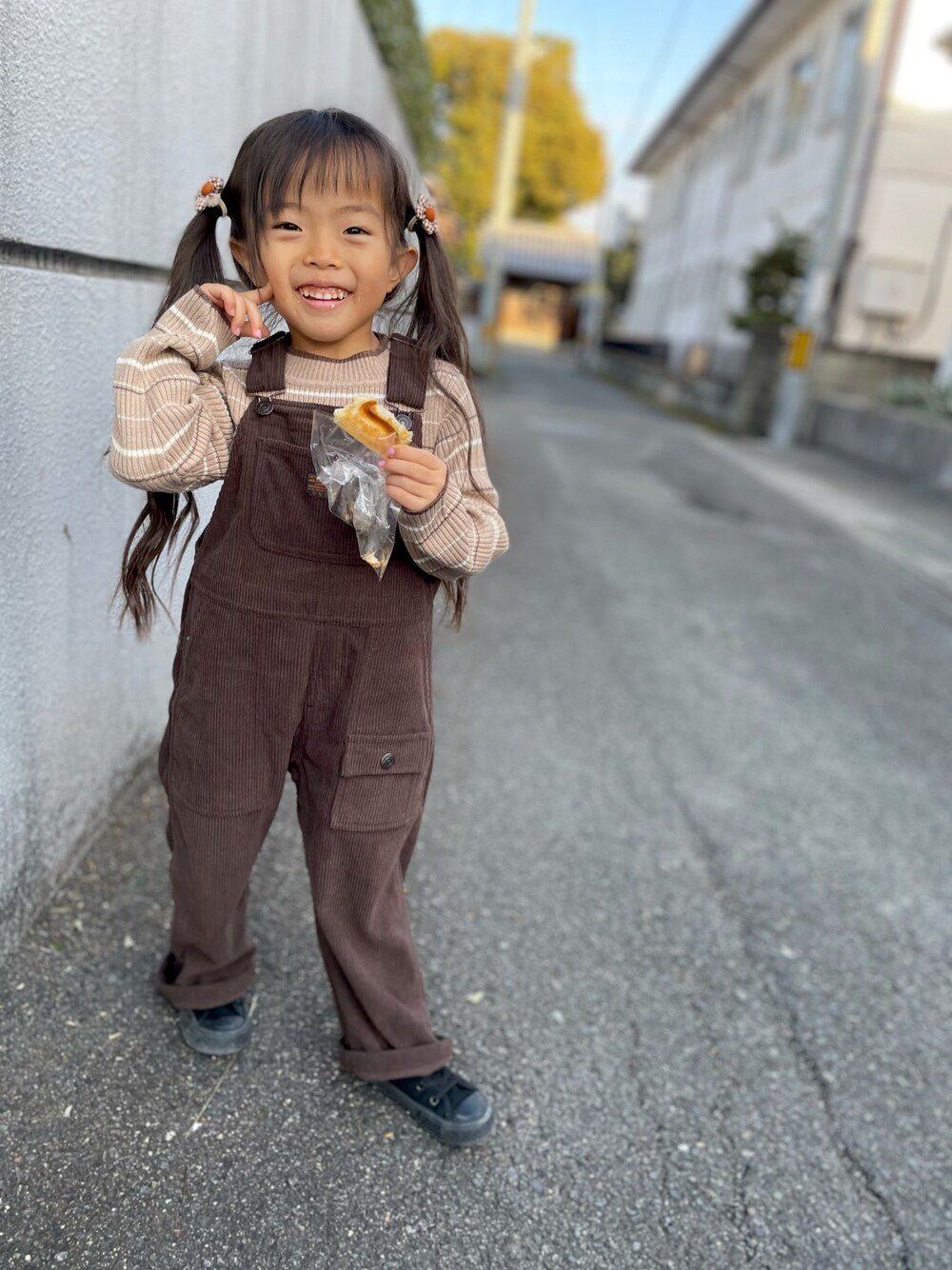 ベージュ系のニット/セーター、ブラウン系のサロペット/オーバーオール、ブラック系のスニーカーを着用したキッズの冬コーディネートの1枚目の写真
