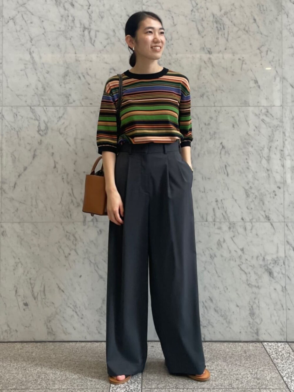 ブラック系のサンダル、ブラック系のニット/セーター、グレー系のスラックスを着用したレディースの夏コーディネートの1枚目の写真