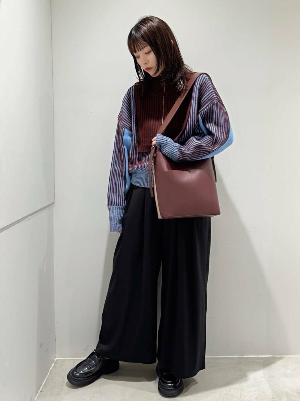 ブルー系のニット/セーター、ブラウン系のショルダーバッグ、ブラック系のローファーを着用したレディースの秋コーディネートの1枚目の写真