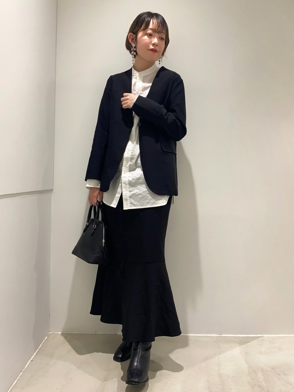 ホワイト系のシャツ/ブラウス、ブラック系のノーカラージャケット、ブラック系のスカートを着用したレディースの秋コーディネートの1枚目の写真