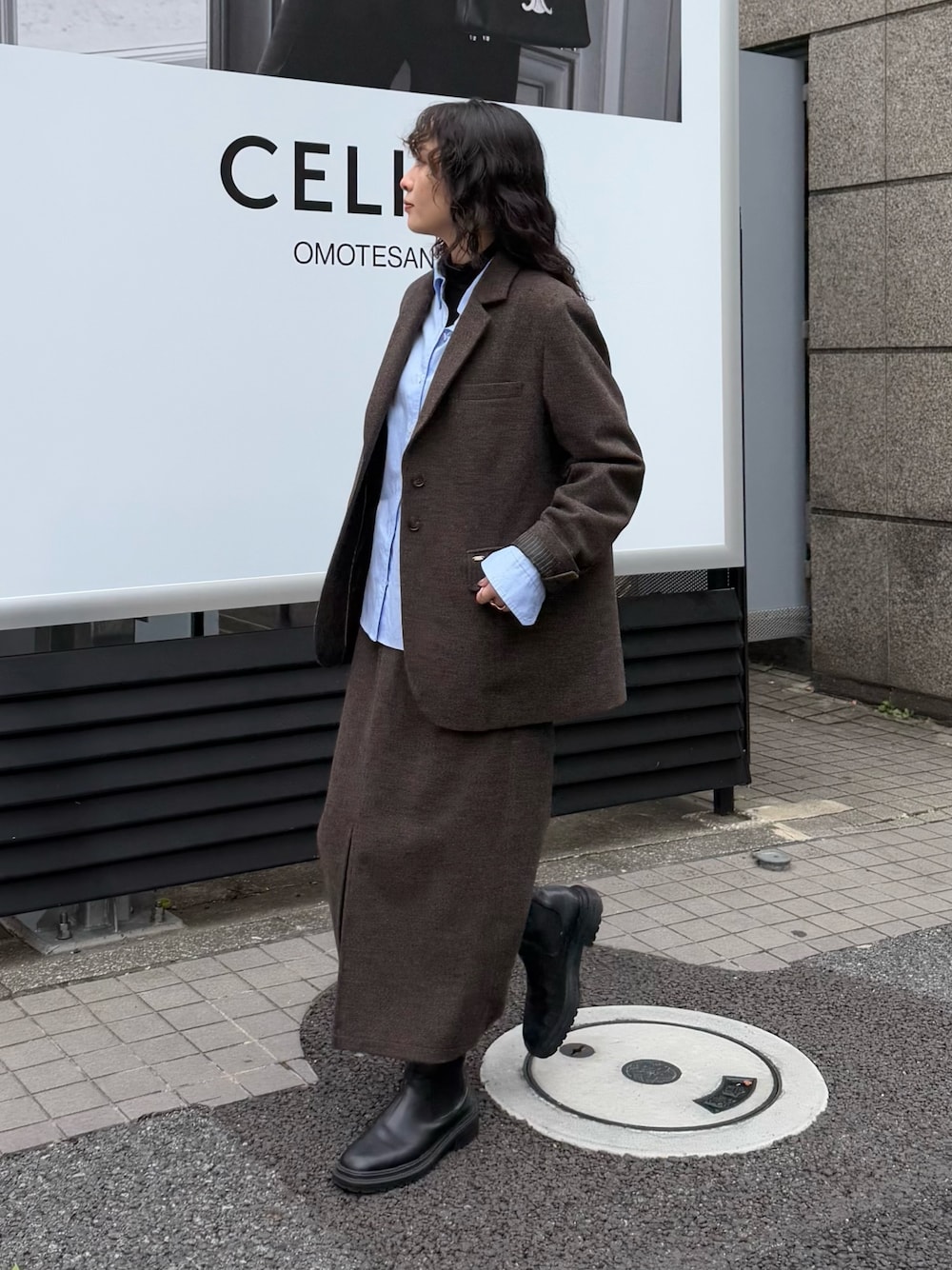 ブラウン系のテーラードジャケット、ブルー系のシャツ/ブラウス、ブラウン系のスカートを着用したレディースの秋コーディネートの1枚目の写真