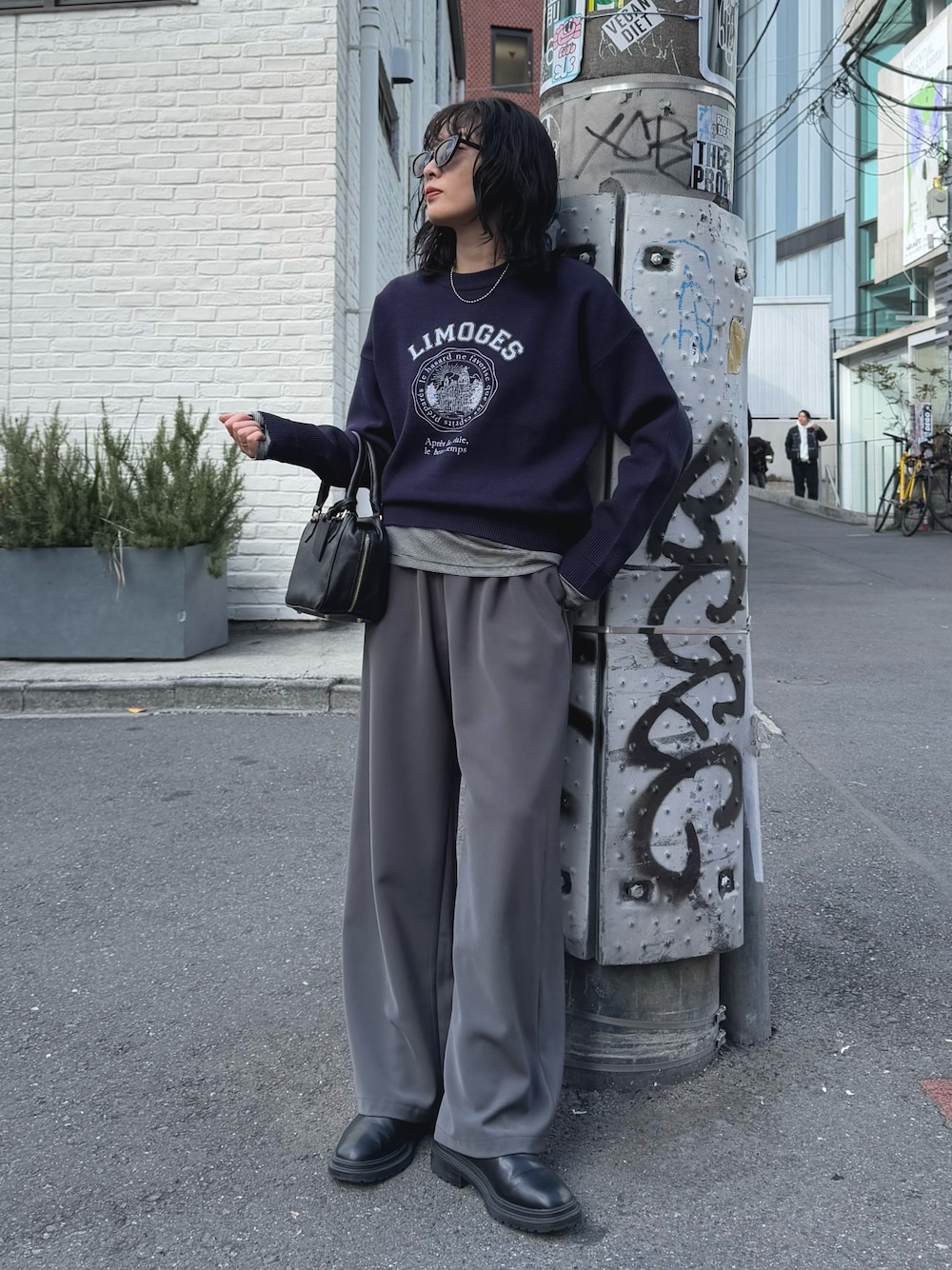 ブルー系のニット/セーター、グレー系のその他パンツ、ブラック系のハンドバッグを着用したレディースの冬コーディネートの1枚目の写真