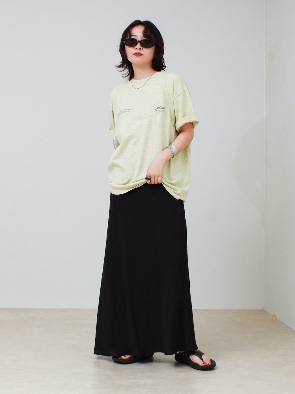 イエロー系のTシャツ/カットソー、ブラック系のスカート、ブラック系のサンダルを着用したレディースの夏コーディネートの1枚目の写真