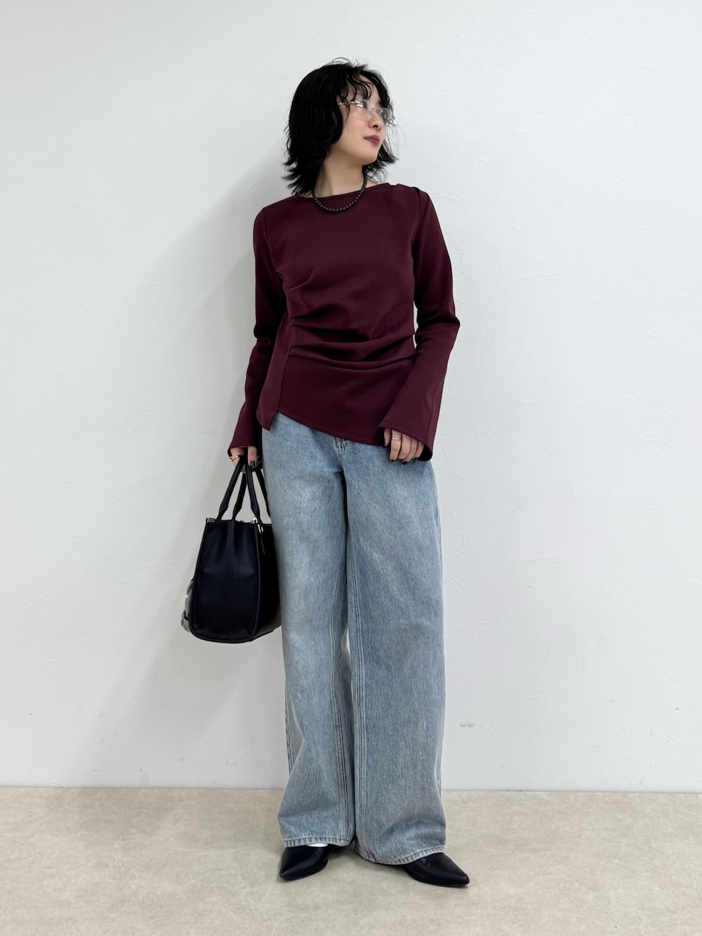 レッド系のTシャツ/カットソー、ブルー系のデニムパンツ、ブラック系のボストンバッグを着用したレディースの秋コーディネートの1枚目の写真