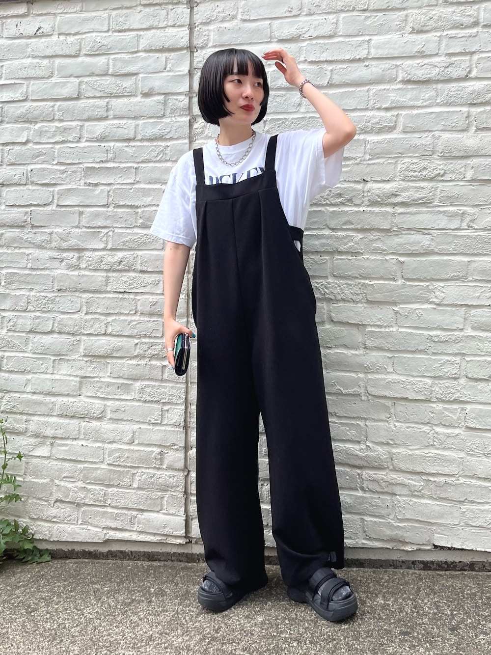 ホワイト系のTシャツ/カットソー、ブラック系のサロペット/オーバーオール、ブラック系のサンダルを着用したレディースの夏コーディネートの1枚目の写真