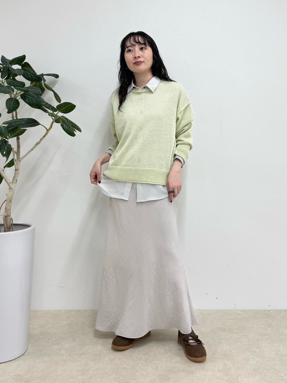 グレー系のシャツ/ブラウス、グリーン系のニット/セーター、ベージュ系のスカートを着用したレディースの春コーディネートの1枚目の写真