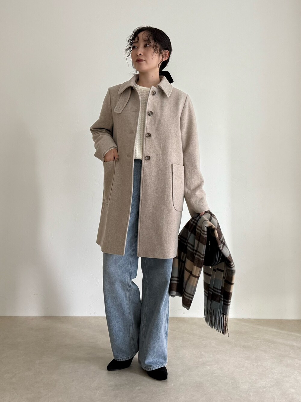 ベージュ系のダッフルコート、ホワイト系のニット/セーター、ブルー系のデニムパンツを着用したレディースの秋コーディネートの1枚目の写真