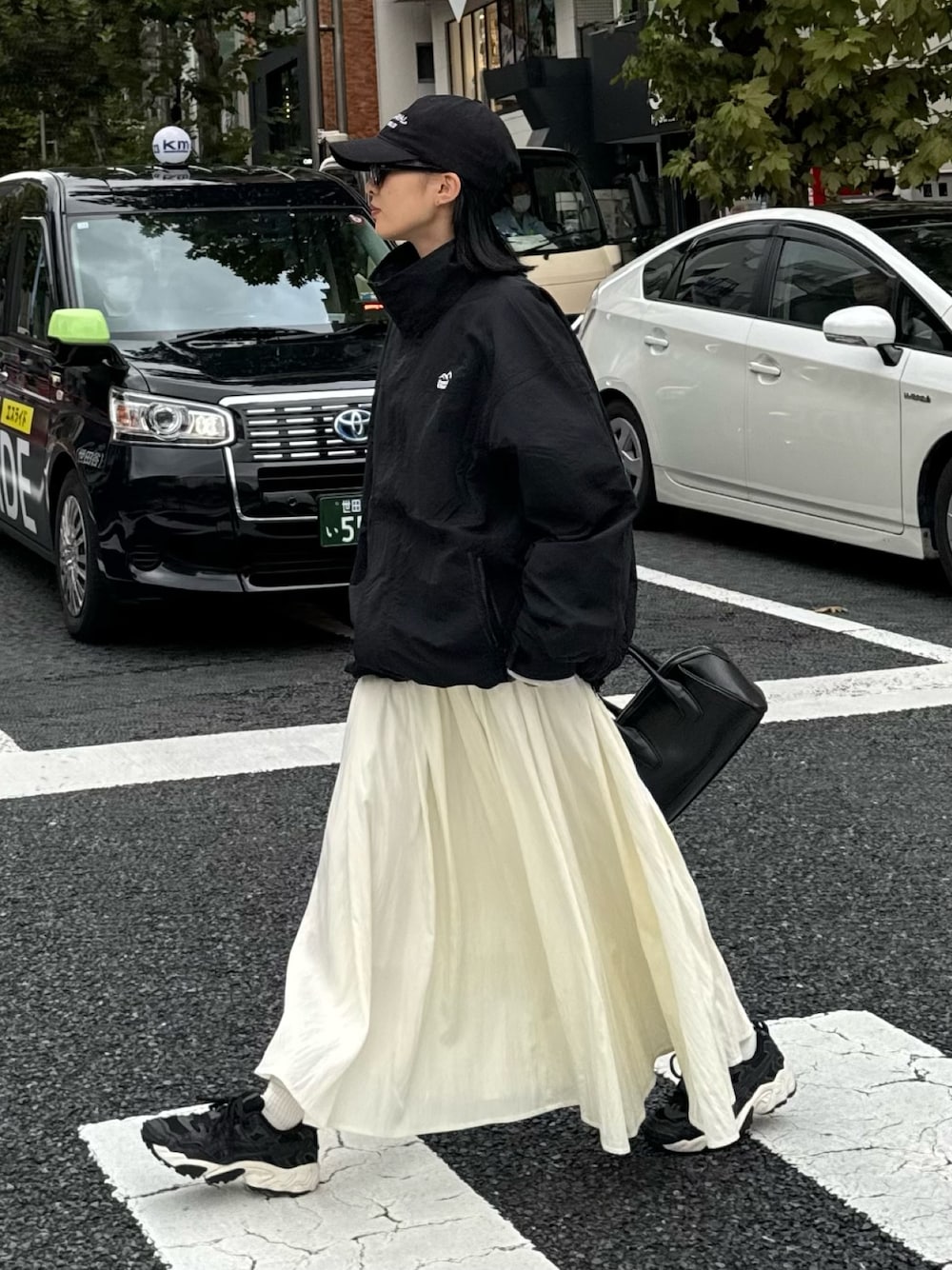 ホワイト系のスカート、グレー系のスウェット、ブラック系のマウンテンパーカーを着用したレディースの秋コーディネートの1枚目の写真