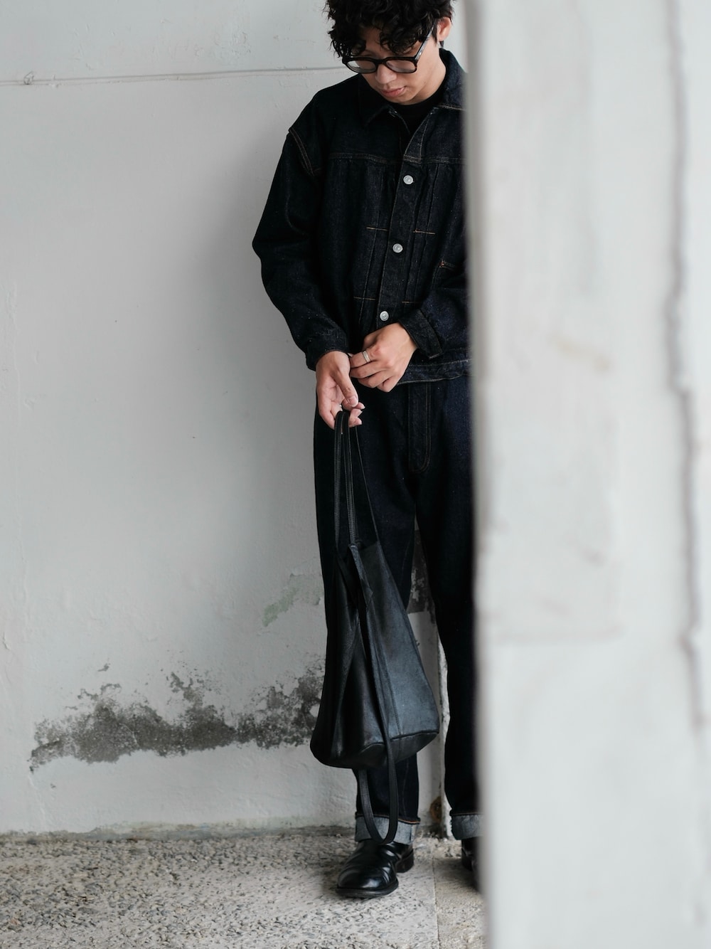 ブルー系のデニムパンツ、ブラック系のブーツ、ブラック系のトートバッグを着用したメンズの冬コーディネートの1枚目の写真