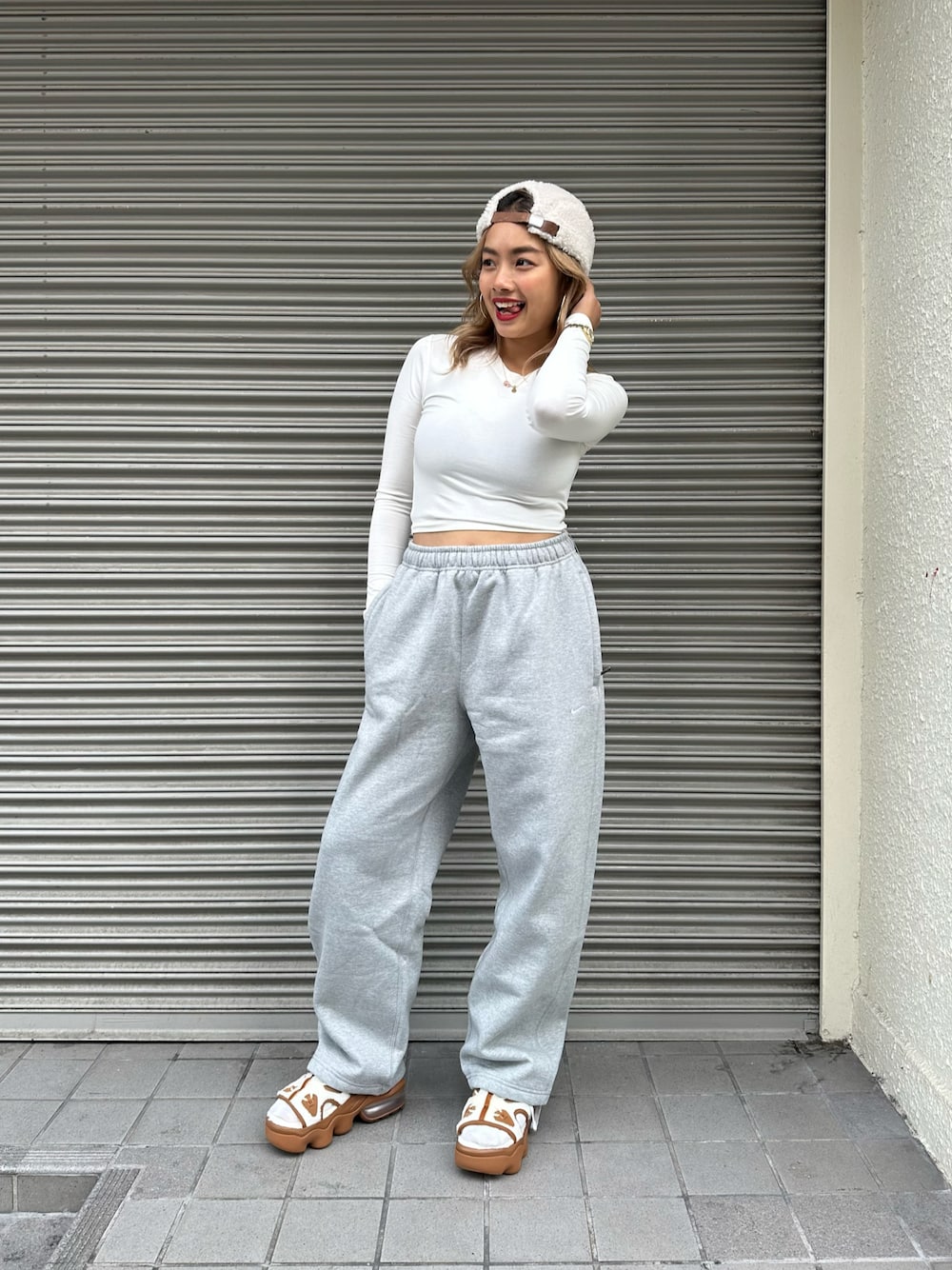 ホワイト系のTシャツ/カットソー、ブラウン系のサンダル、グレー系のスウェットパンツを着用したレディースの秋コーディネートの1枚目の写真