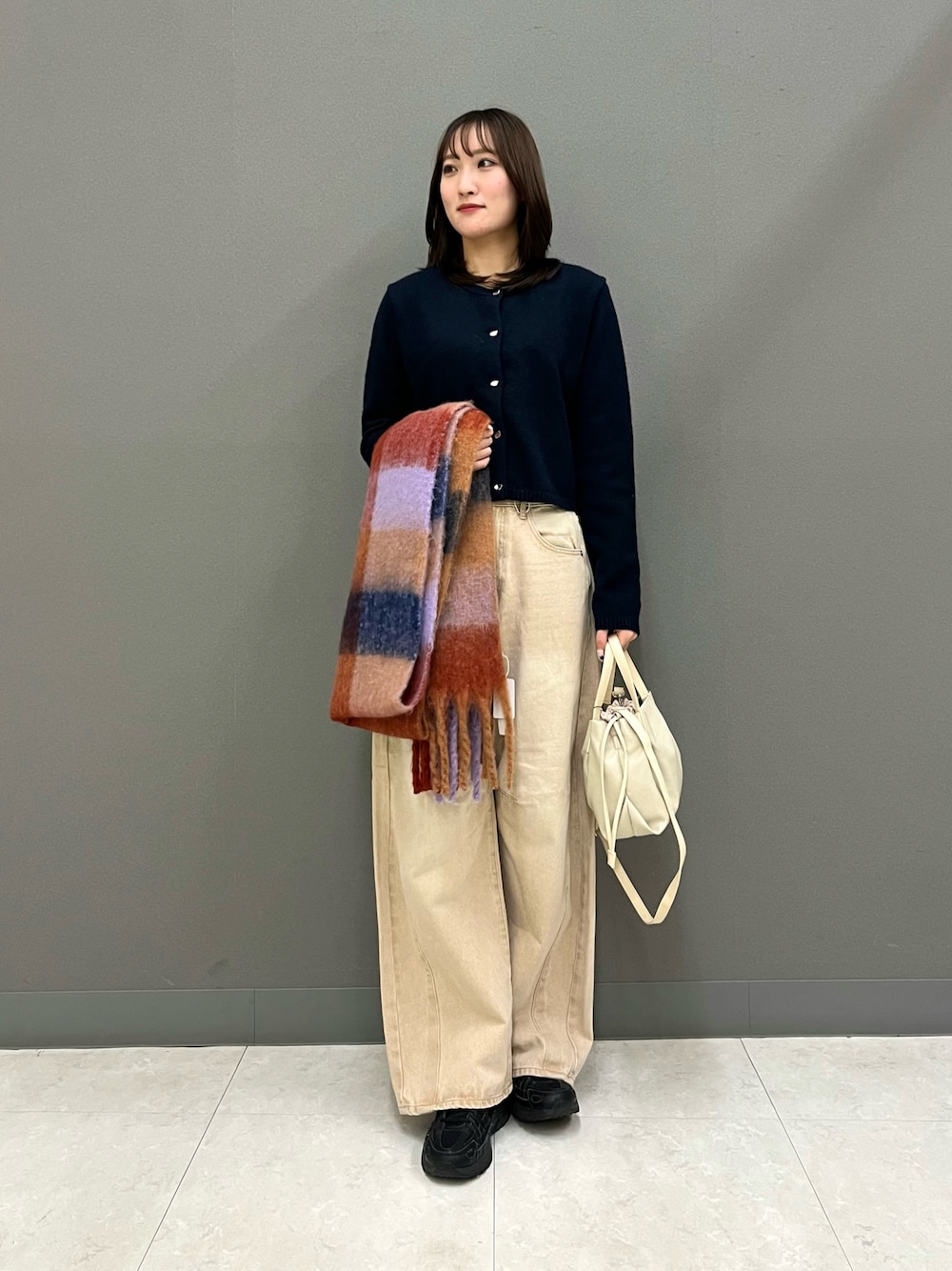 ブルー系のカーディガン/ボレロ、ベージュ系のデニムパンツ、ホワイト系のショルダーバッグを着用したレディースの冬コーディネートの1枚目の写真