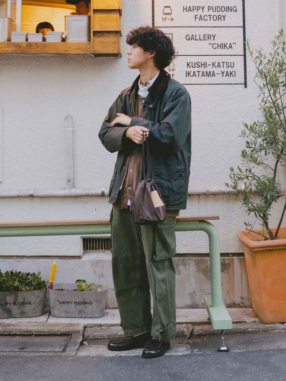 グリーン系のブルゾン、ベージュ系のベスト、グリーン系のカーゴパンツを着用したメンズの秋コーディネートの1枚目の写真