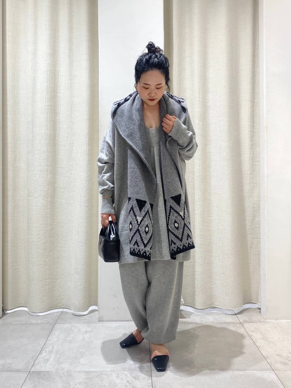 グレー系のニット/セーター、ブラウン系のトレンチコート、グレー系のスウェットパンツを着用したレディースの秋コーディネートの1枚目の写真