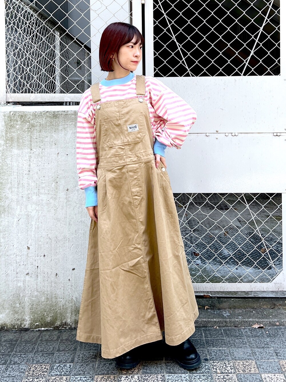 ピンク系のTシャツ/カットソー、ベージュ系のジャンパースカートを着用したレディースの秋コーディネートの1枚目の写真