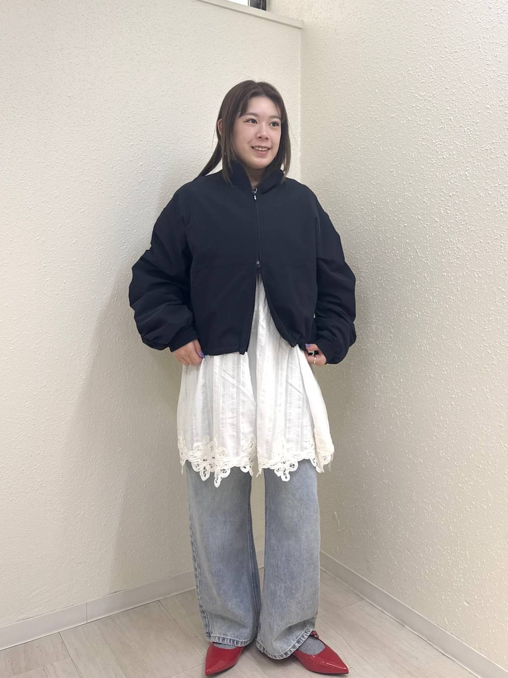レッド系のパンプス、ブルー系のデニムパンツ、ブラック系のブルゾンを着用したレディースの春コーディネートの1枚目の写真