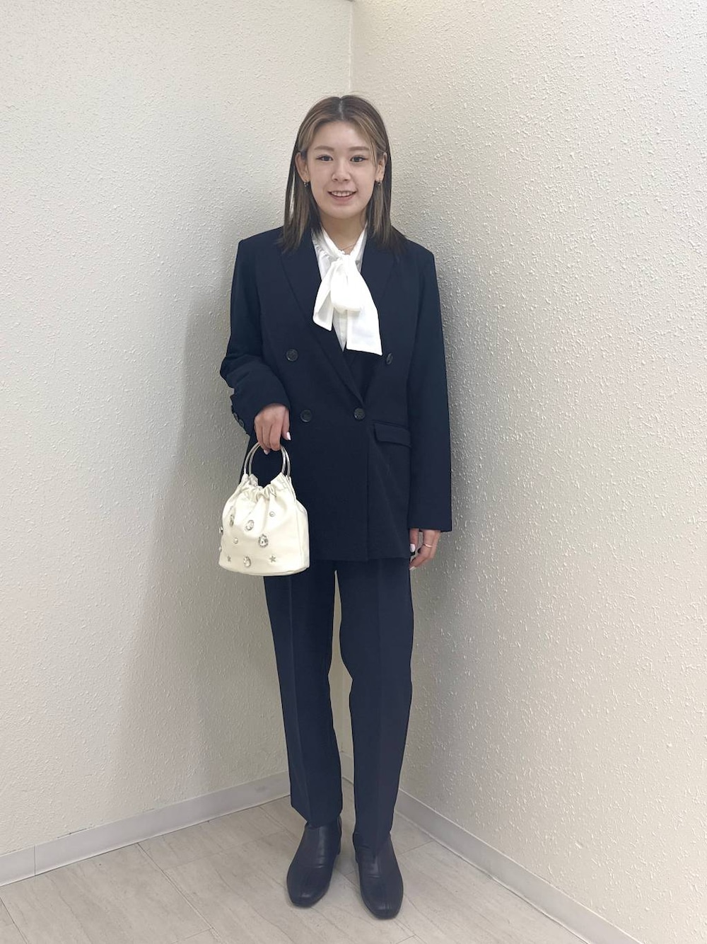 ブラック系のブーツ、ホワイト系のハンドバッグ、ブルー系のテーラードジャケットを着用したレディースの冬コーディネートの1枚目の写真