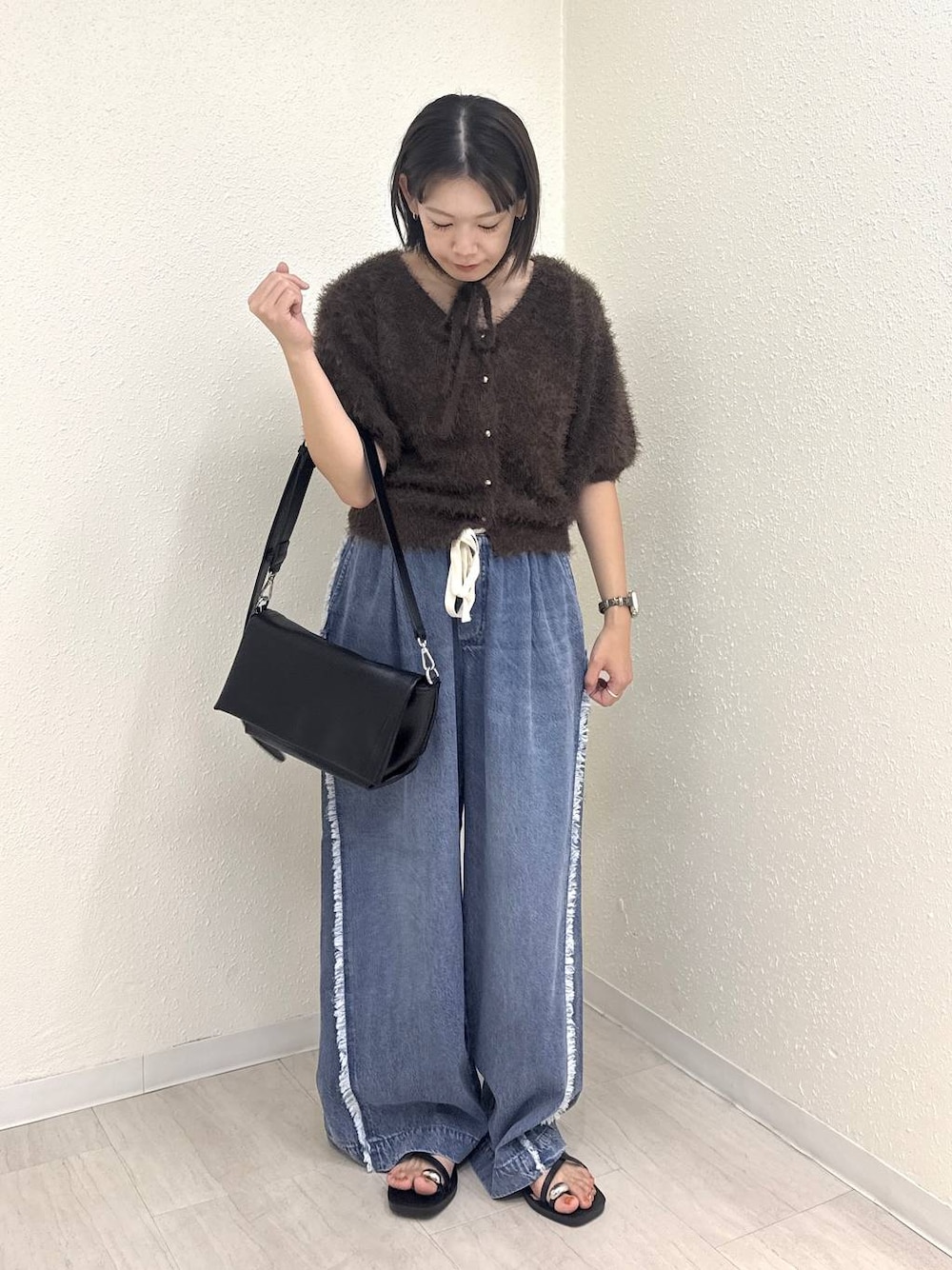 ブラック系のショルダーバッグ、ブラウン系のカーディガン/ボレロ、ブルー系のデニムパンツを着用したレディースの夏コーディネートの1枚目の写真