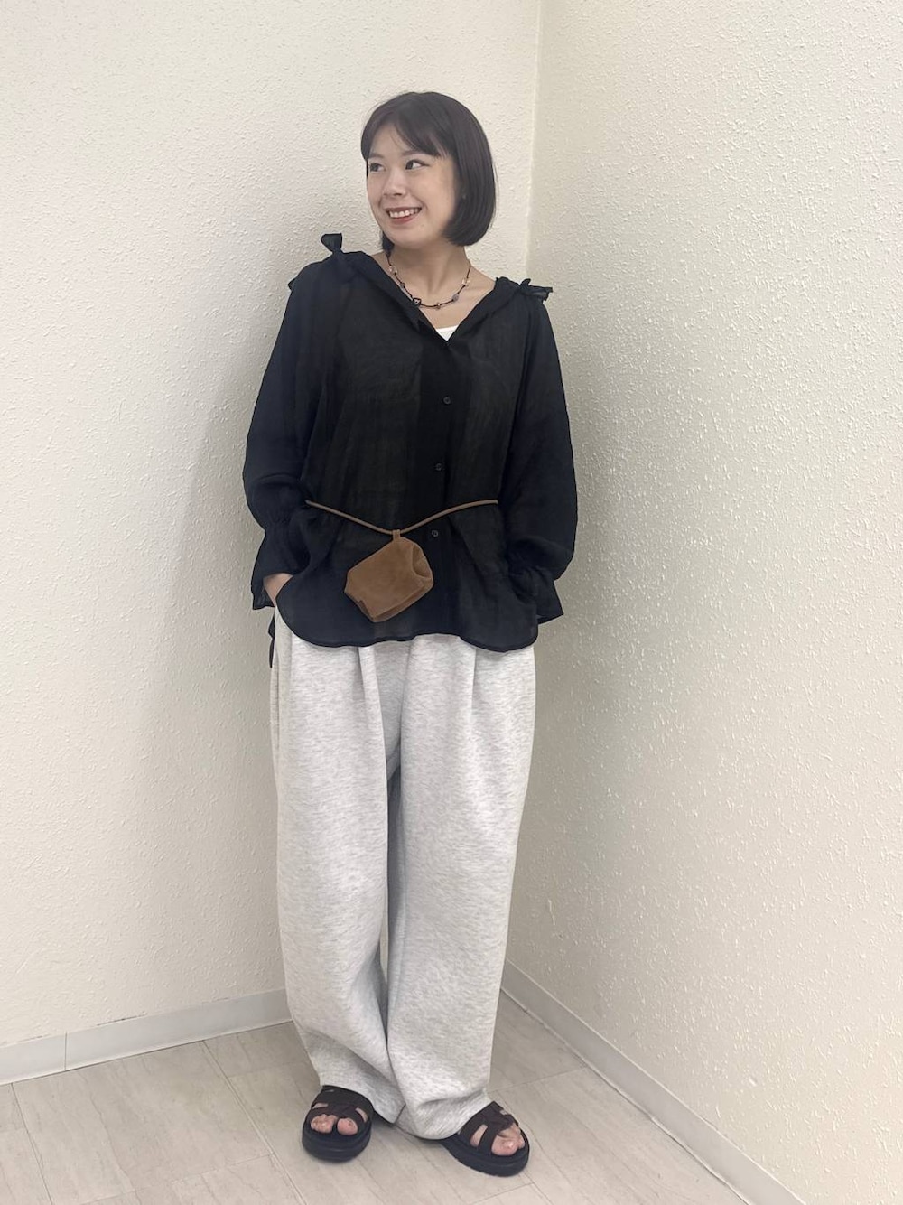 イエロー系のボディバッグ/ウエストポーチ、グレー系のスウェットパンツ、ブラック系のシャツ/ブラウスを着用したレディースの秋コーディネートの1枚目の写真