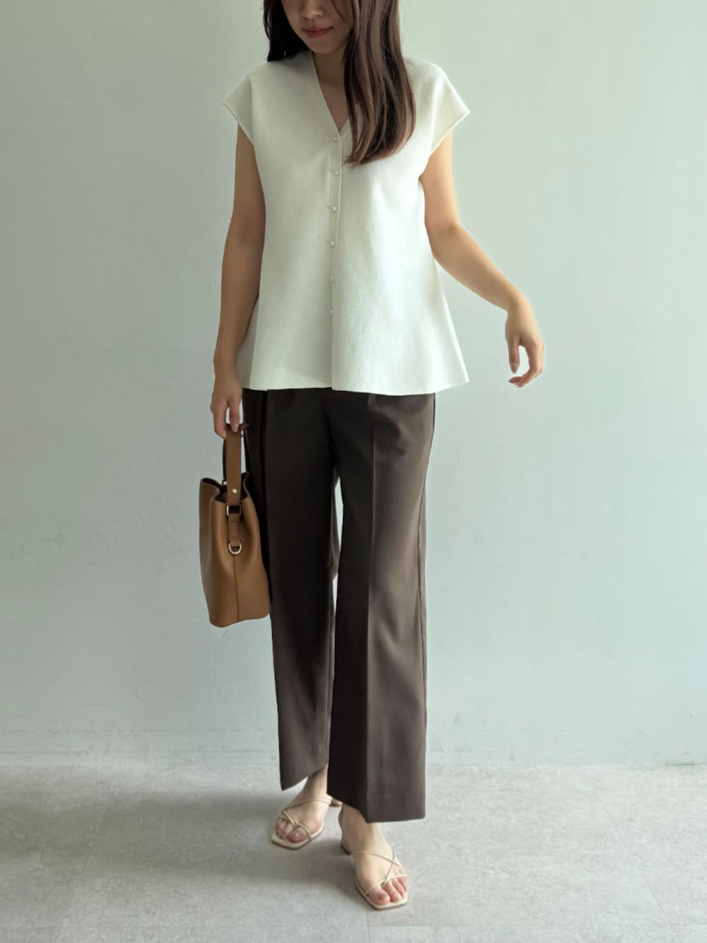 ホワイト系のベスト、ブラウン系のスラックスを着用したレディースの夏コーディネートの1枚目の写真