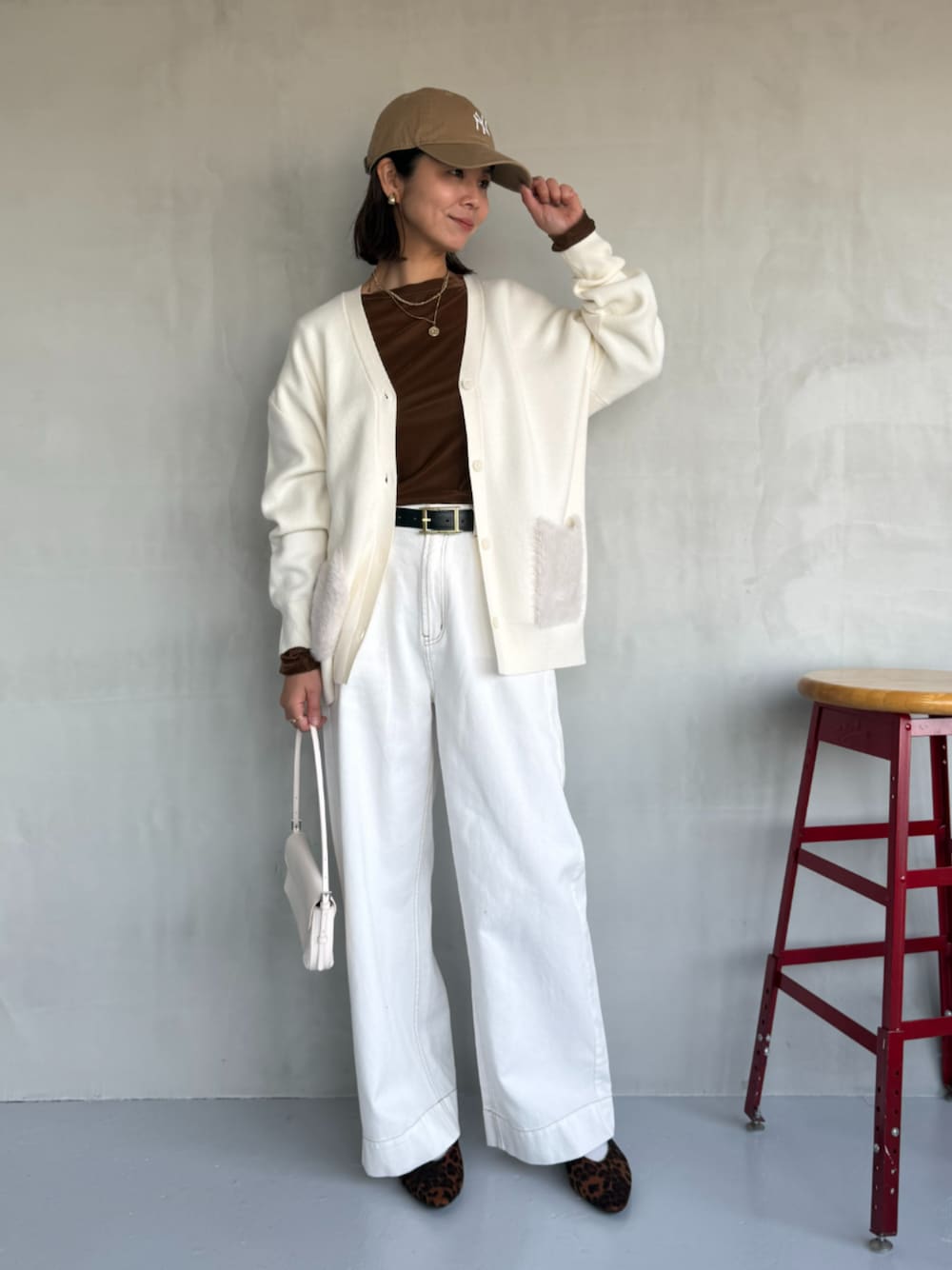 ブラウン系のTシャツ/カットソー、ホワイト系のカーディガン/ボレロ、ホワイト系のデニムパンツを着用したレディースの秋コーディネートの1枚目の写真