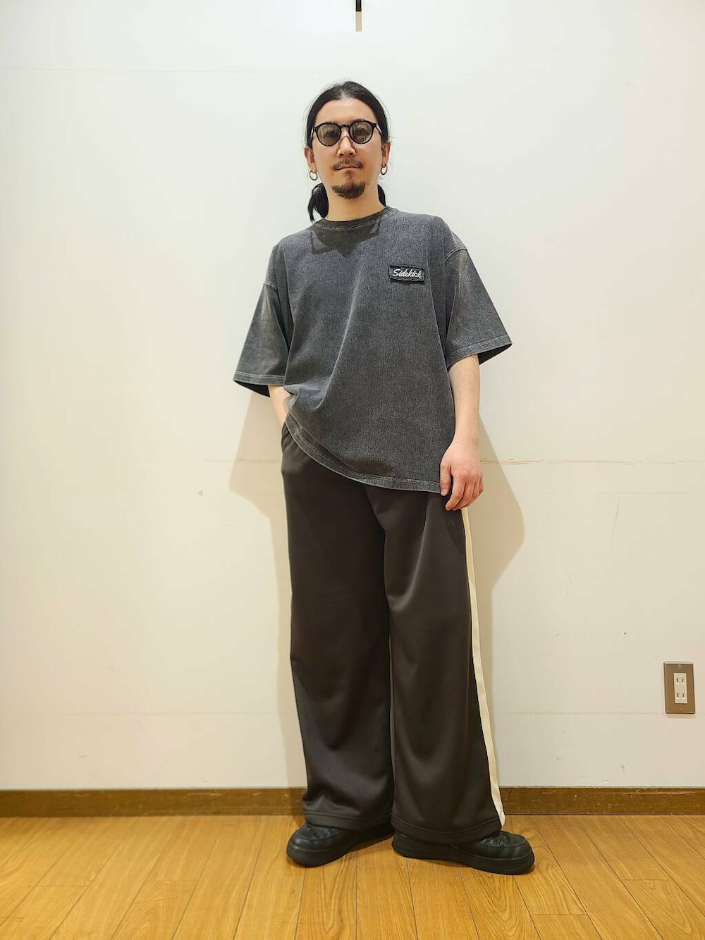 ブラウン系のその他パンツ、ブラック系のTシャツ/カットソー、グリーン系のメガネを着用したメンズの春コーディネートの1枚目の写真