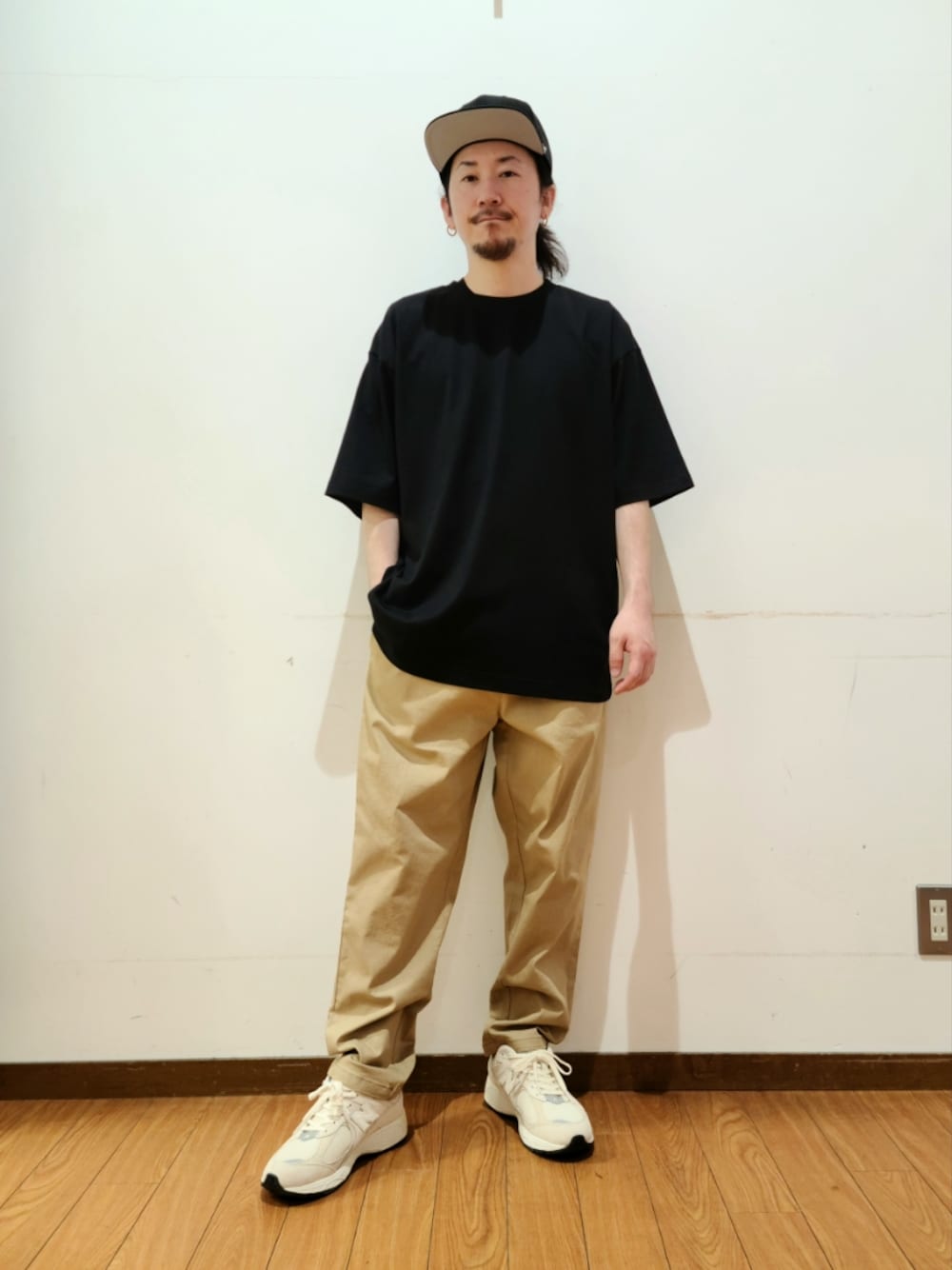 ブラック系のTシャツ/カットソー、ベージュ系のその他パンツ、ブラック系のキャップを着用したメンズの春コーディネートの1枚目の写真