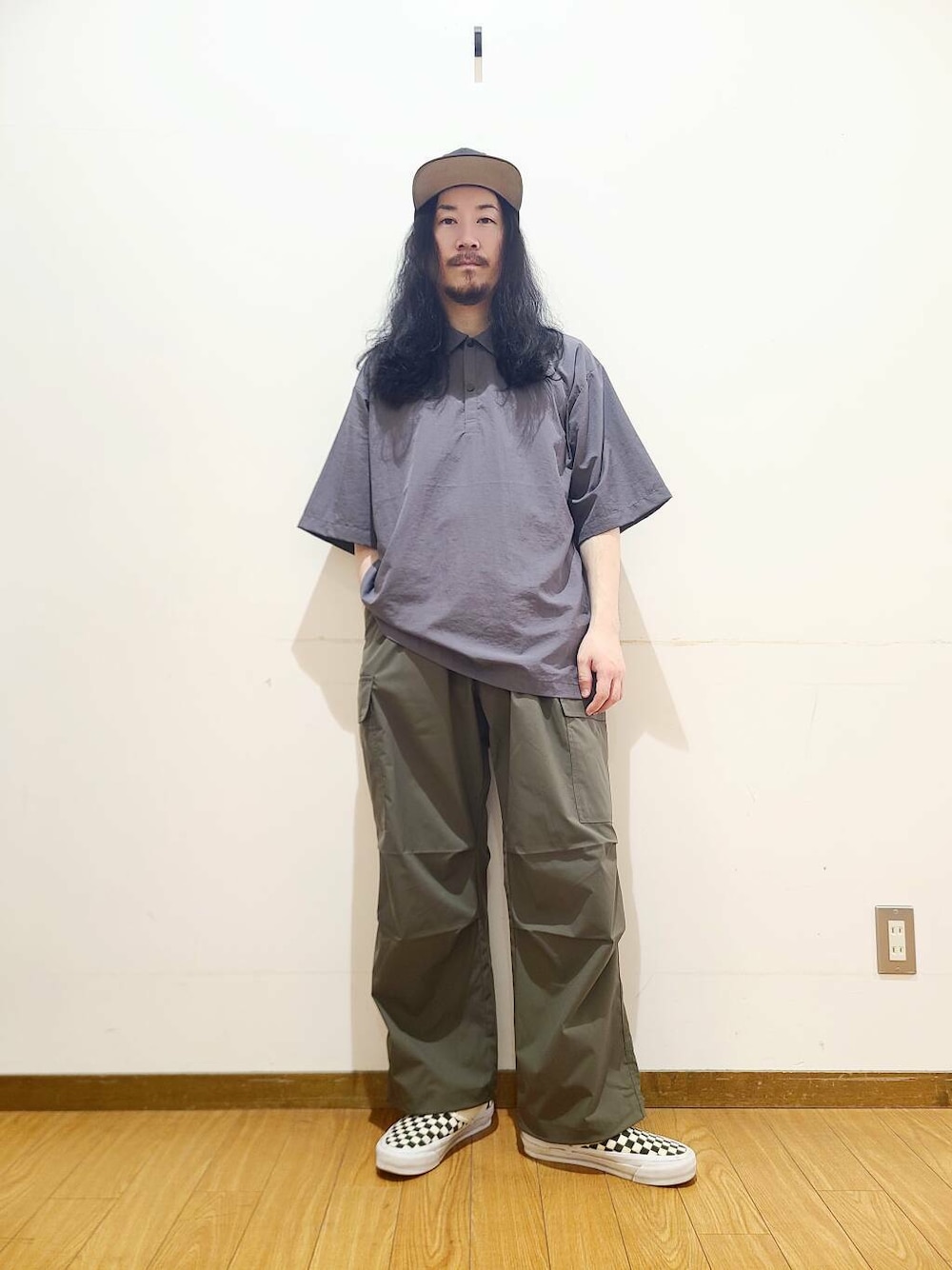 ブラック系のスニーカー、グリーン系のその他パンツ、グレー系のポロシャツを着用したメンズの春コーディネートの1枚目の写真