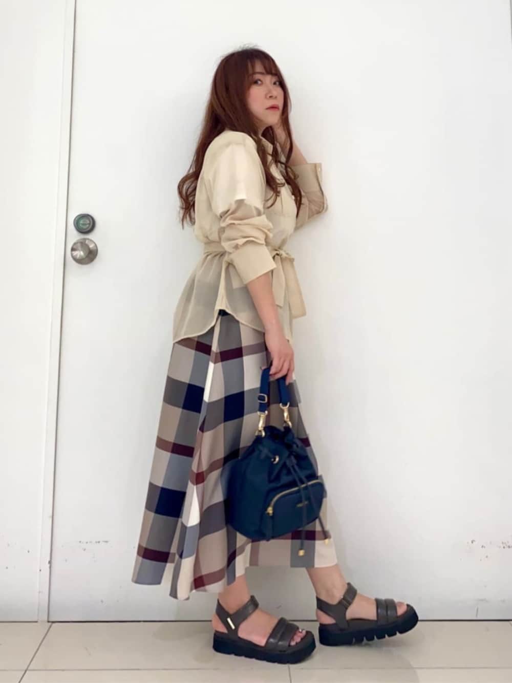 ベージュ系のスカート、ホワイト系のシャツ/ブラウス、ブルー系のショルダーバッグを着用したレディースの秋コーディネートの1枚目の写真