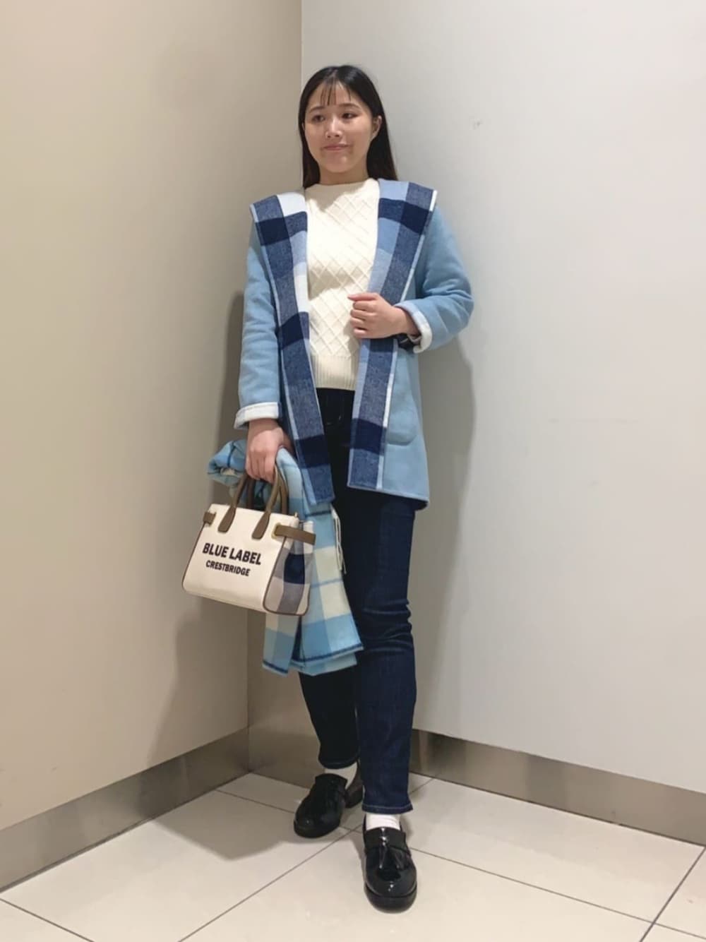 ブラック系のローファー、ホワイト系のトートバッグ、ブルー系のデニムパンツを着用したレディースの秋コーディネートの1枚目の写真