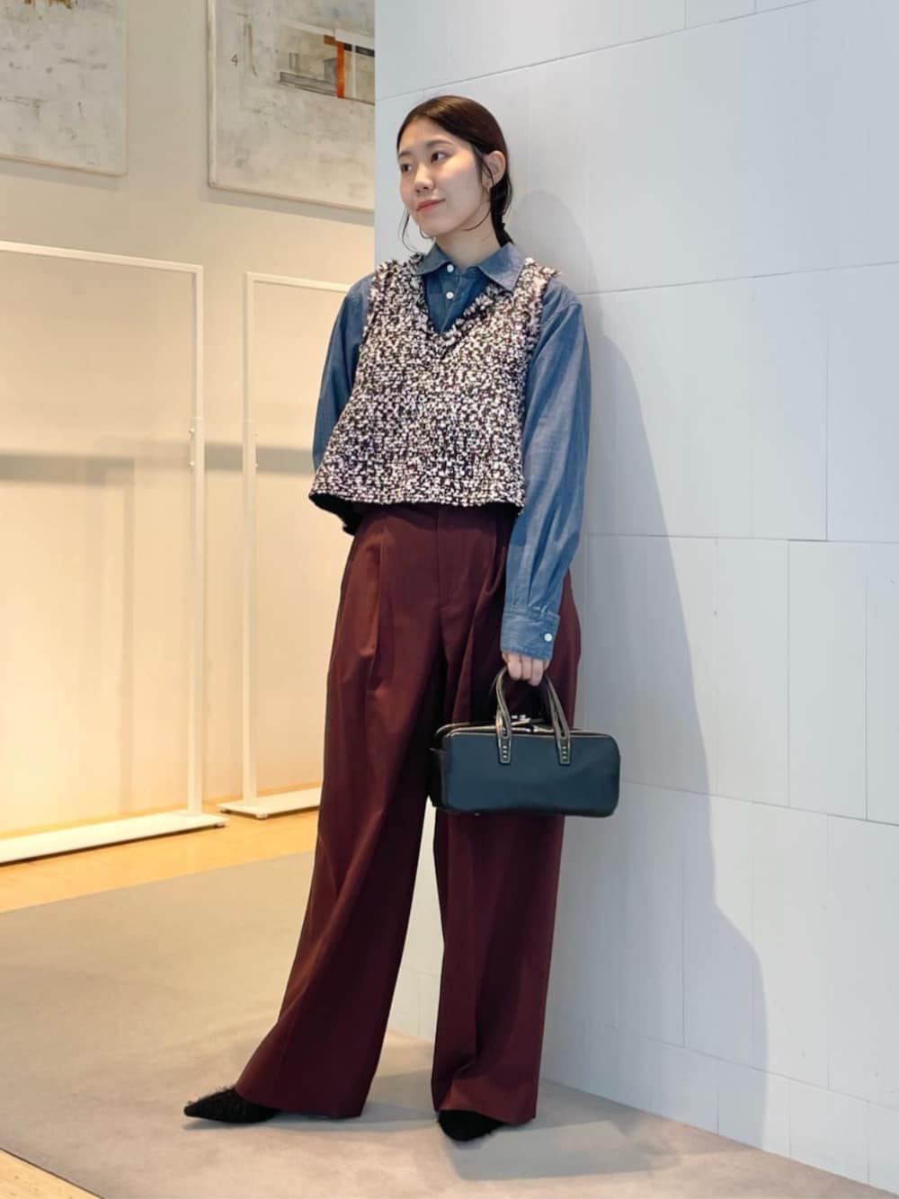 レッド系のスラックス、ブルー系のシャツ/ブラウス、ブラック系のベストを着用したレディースの秋コーディネートの1枚目の写真