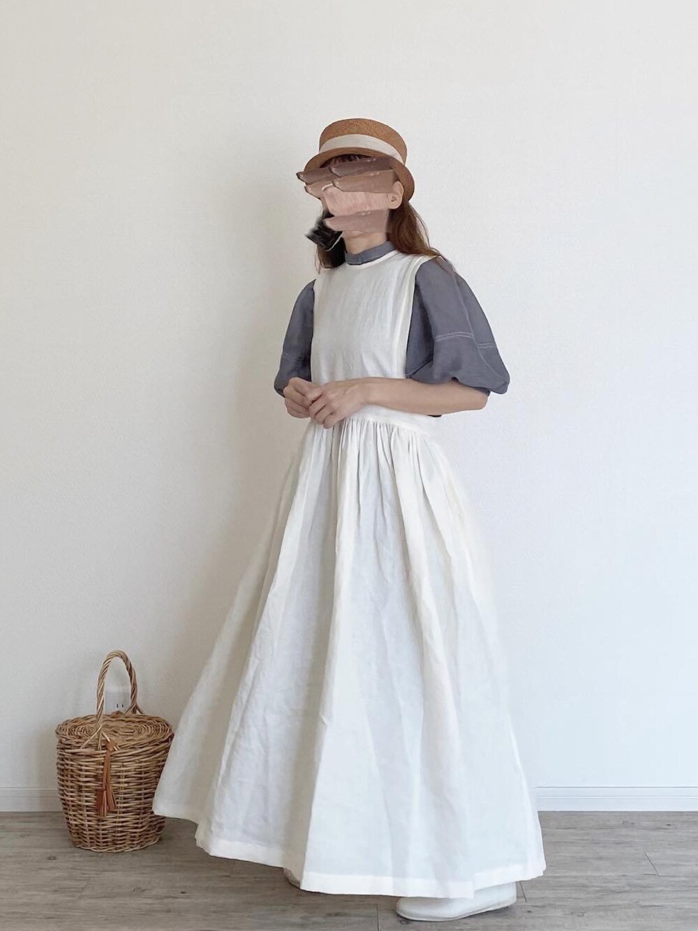 グレー系のシャツ/ブラウス、ホワイト系のジャンパースカート、ベージュ系のかごバッグを着用したレディースの秋コーディネートの1枚目の写真