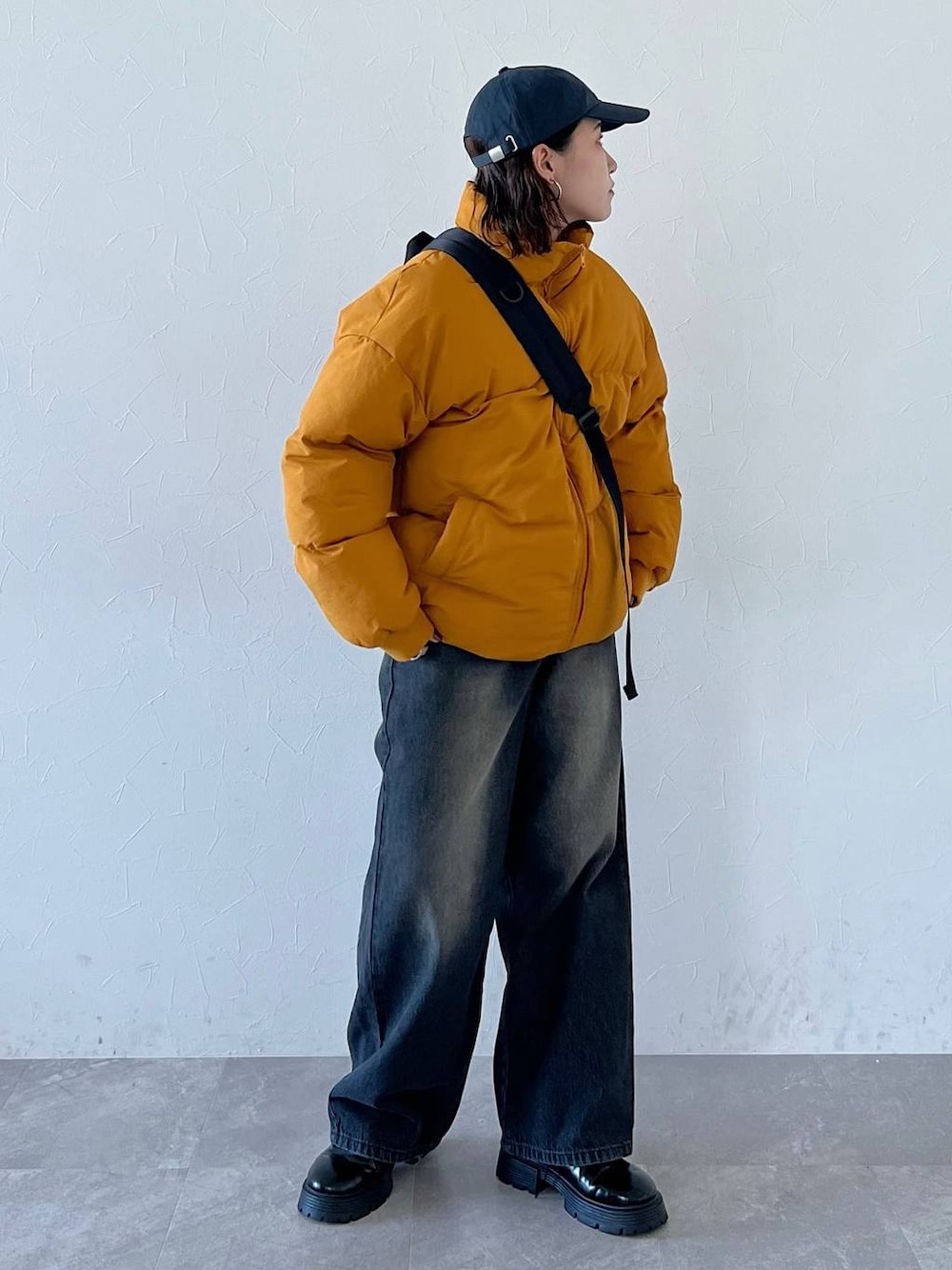 ブラック系のその他シューズ、ブラック系のデニムパンツ、イエロー系のダウンジャケット/コートを着用したレディースの秋コーディネートの1枚目の写真