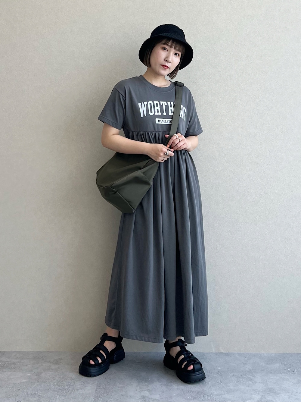 グリーン系のショルダーバッグ、ブラック系のサンダル、グレー系のワンピースを着用したレディースの春コーディネートの1枚目の写真