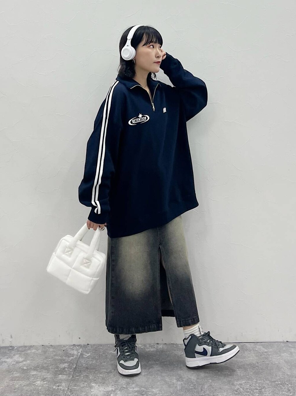 ホワイト系のハンドバッグ、ブラック系のスカート、ブルー系のスウェットを着用したレディースの秋コーディネートの1枚目の写真