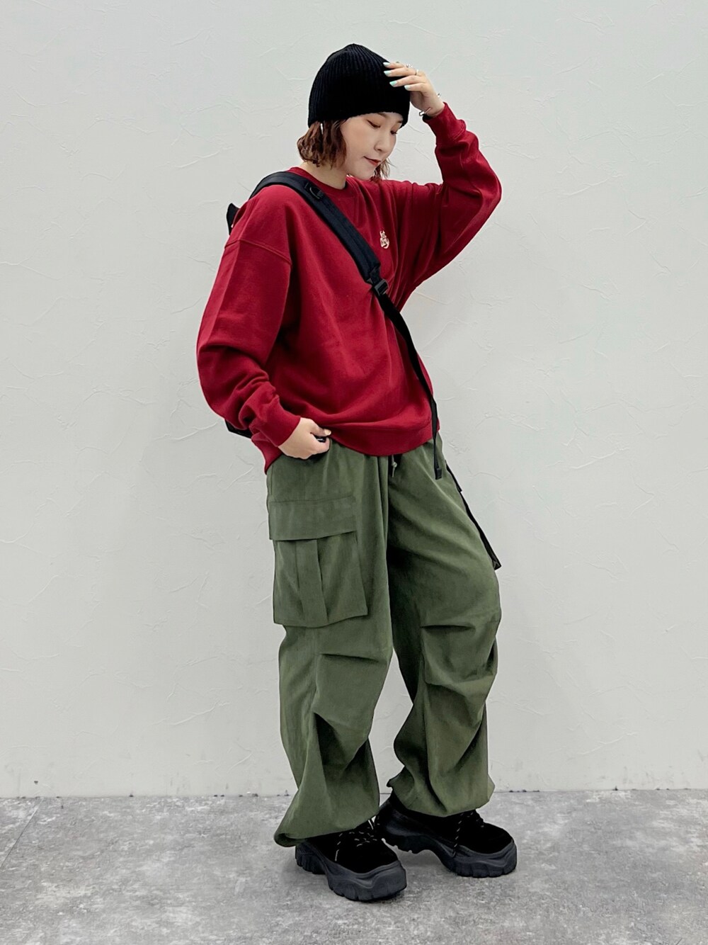 グリーン系のカーゴパンツ、レッド系のスウェット、ブラック系のニットキャップ/ビーニーを着用したレディースの秋コーディネートの1枚目の写真