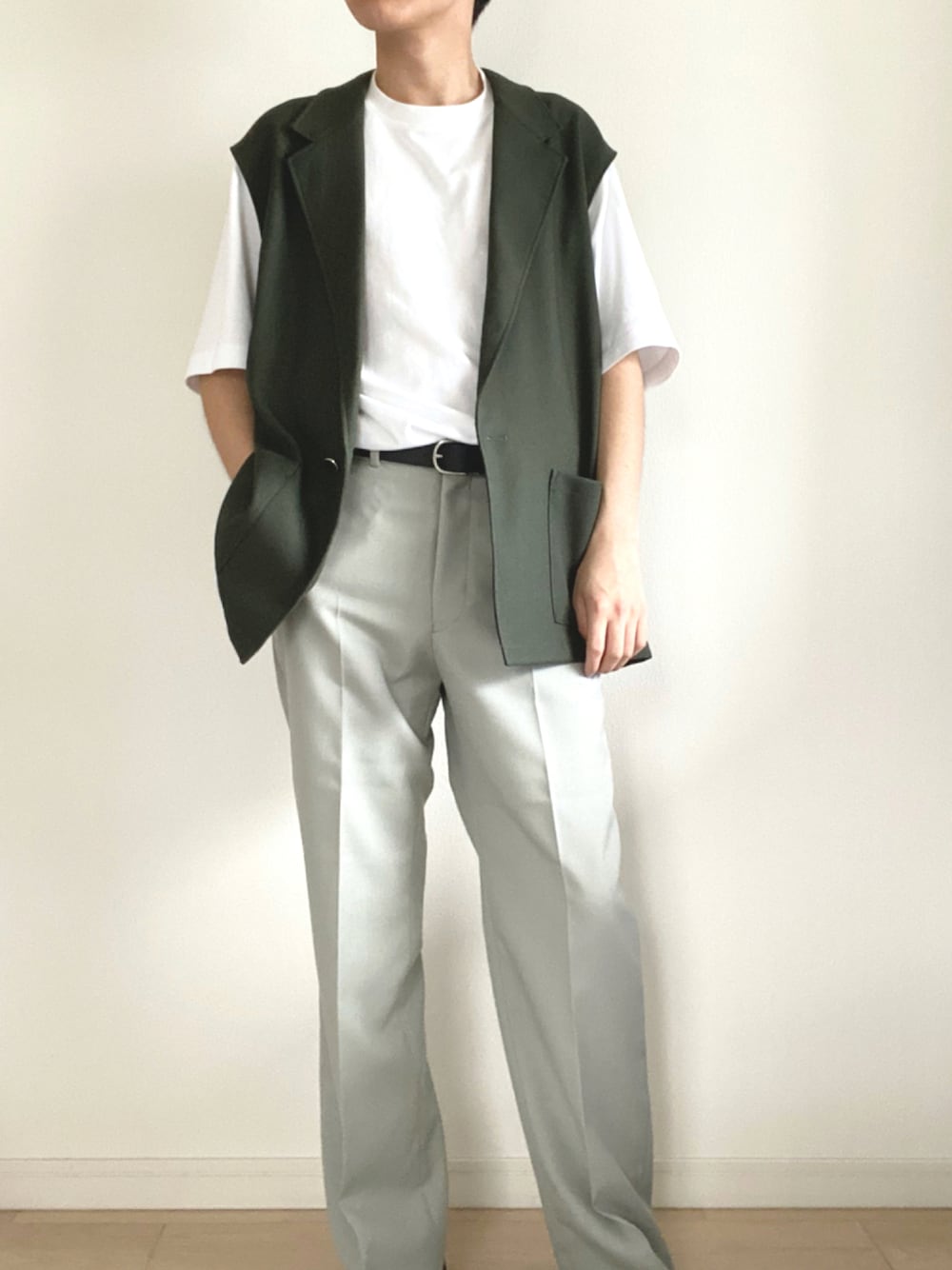 グレー系のスラックス、グリーン系のベスト、ホワイト系のTシャツ/カットソーを着用したメンズの秋コーディネートの1枚目の写真