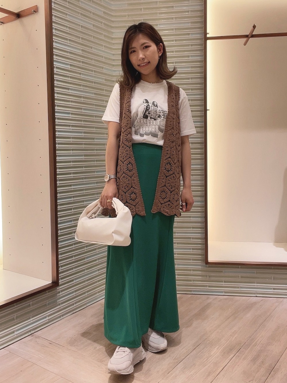 ホワイト系のTシャツ/カットソー、グリーン系のスカート、ブラウン系のベストを着用したレディースの春コーディネートの1枚目の写真