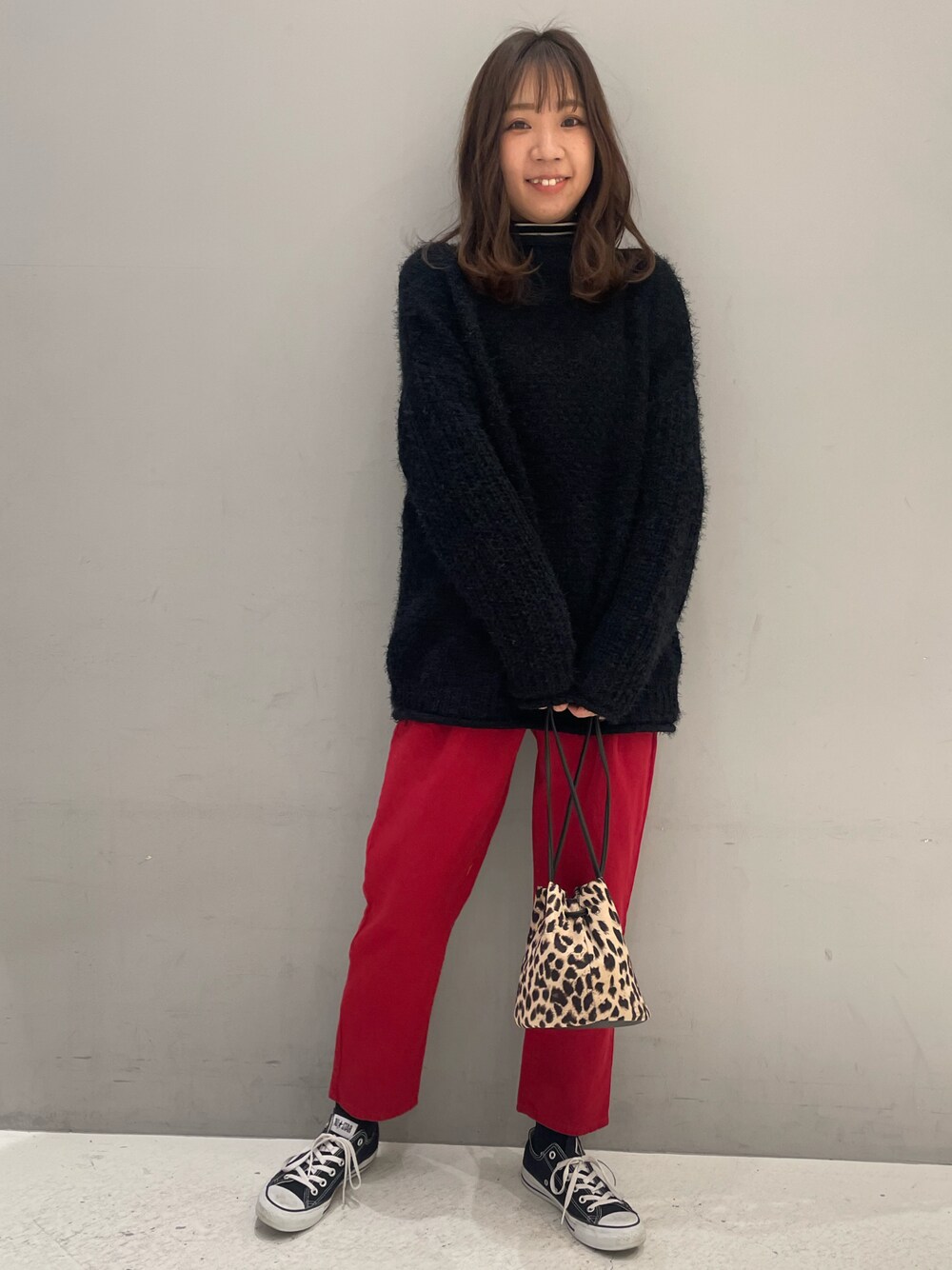 ブラック系のニット/セーター、レッド系のスラックスを着用したレディースの冬コーディネートの1枚目の写真